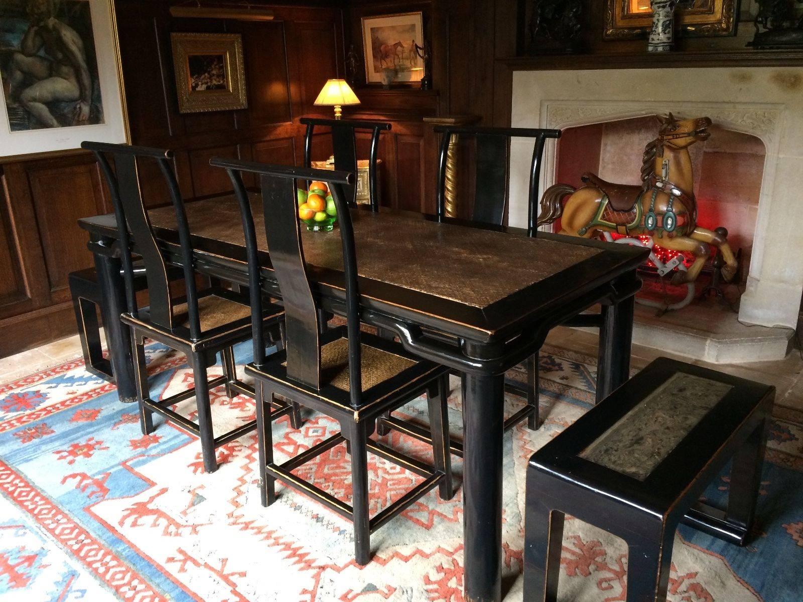 A Chinese Ming style ebonized solid elm dining suite, comprising rattan lined table, four yoke-back rattan seated dining chairs and a pair of benches set with hard stone panel (total seven pieces), the rattan on the dining table has ever so slight