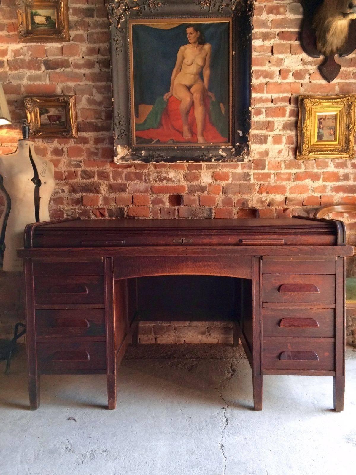 An early 20th century oak Globe Wernicke kneehole twin pedestal desk with shallow tambour roll top over a panelled frame fitted with five drawers (disguised as six) raised on square tapered supports, comes with key and tassel.