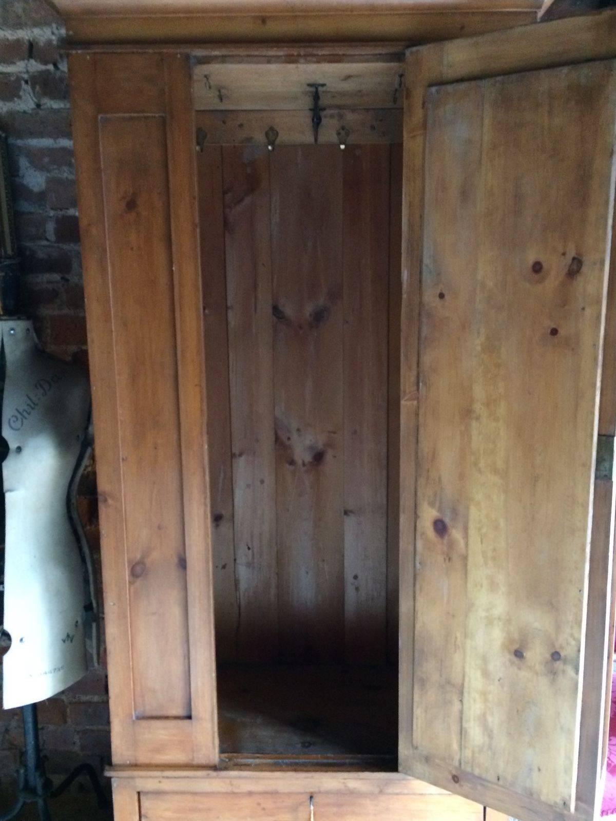A fabulous antique Edwardian satin walnut single wardrobe circa 1900, being raised on a plinth drawer base with original brass handles, mirror glass door to centre with hanging hooks and small rail within, flared cornice atop with spindle gallery