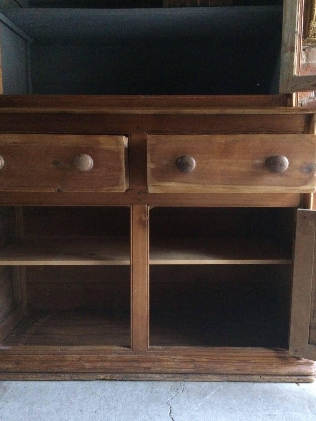 Antique Victorian antique pine two-door bookcase cabinet, corniced top over two glazed doors with two shelves inside, over base with two frieze drawers over two cupboard doors with later added shelves within, raised on a plinth base, the upper part