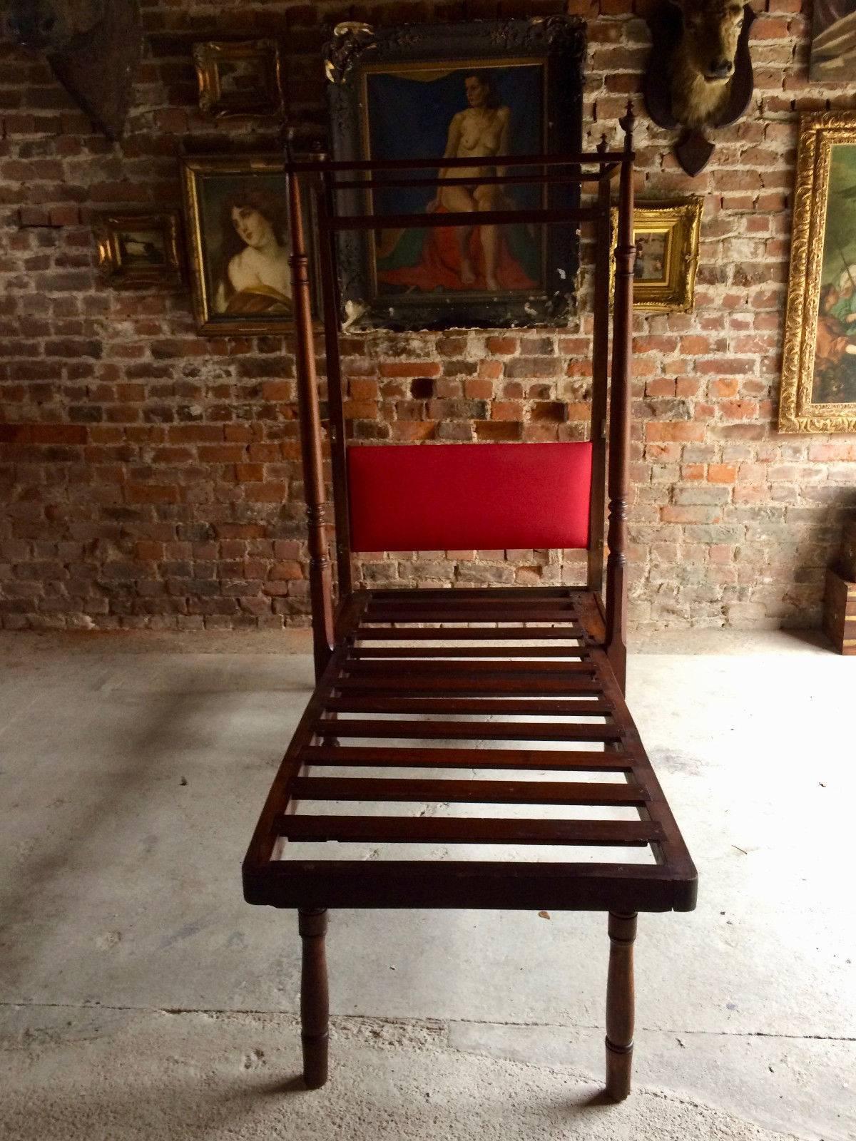 A beautiful antique early 19th century George III Campaign bed, circa 1820, the corner posts with large turned finials, the head board covered in a deep red fabric, typical four post canopy for mosquito netting above, the bed folds up to increase