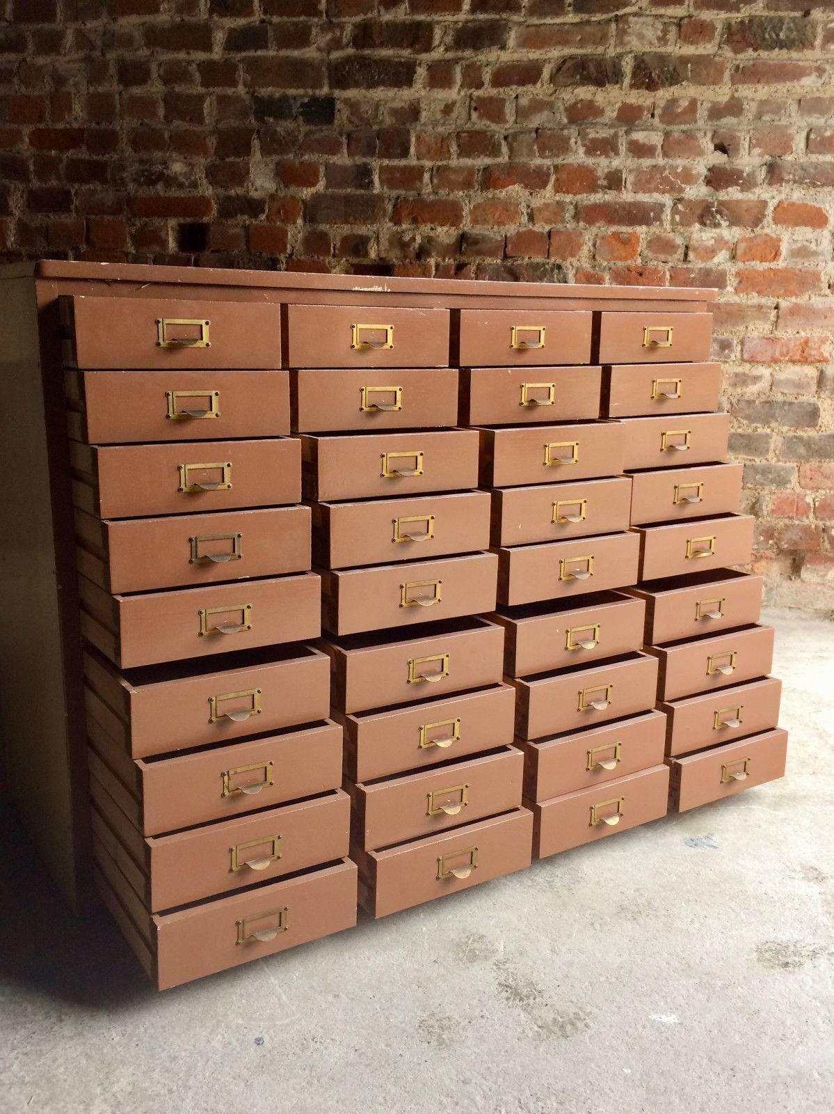 A fabulous Mid-Century Haberdashery solid pine bank of drawers, bank of 36 drawers with brass card holder fittings, rectangular top over four rows each with nine pull-out drawers, chocolate brown distressed paintwork.