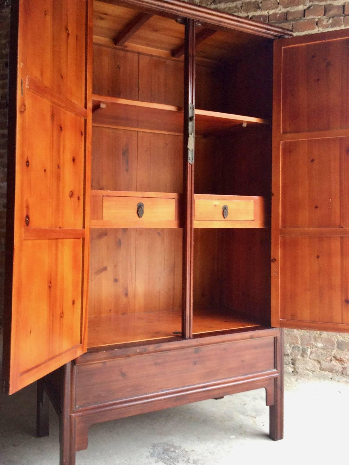 A beautiful Chinese stained pine wardrobe, a pair of doors enclosing two drawers and a shelved interior, raised on stile legs, comes with door bar and tassel looks amazing.