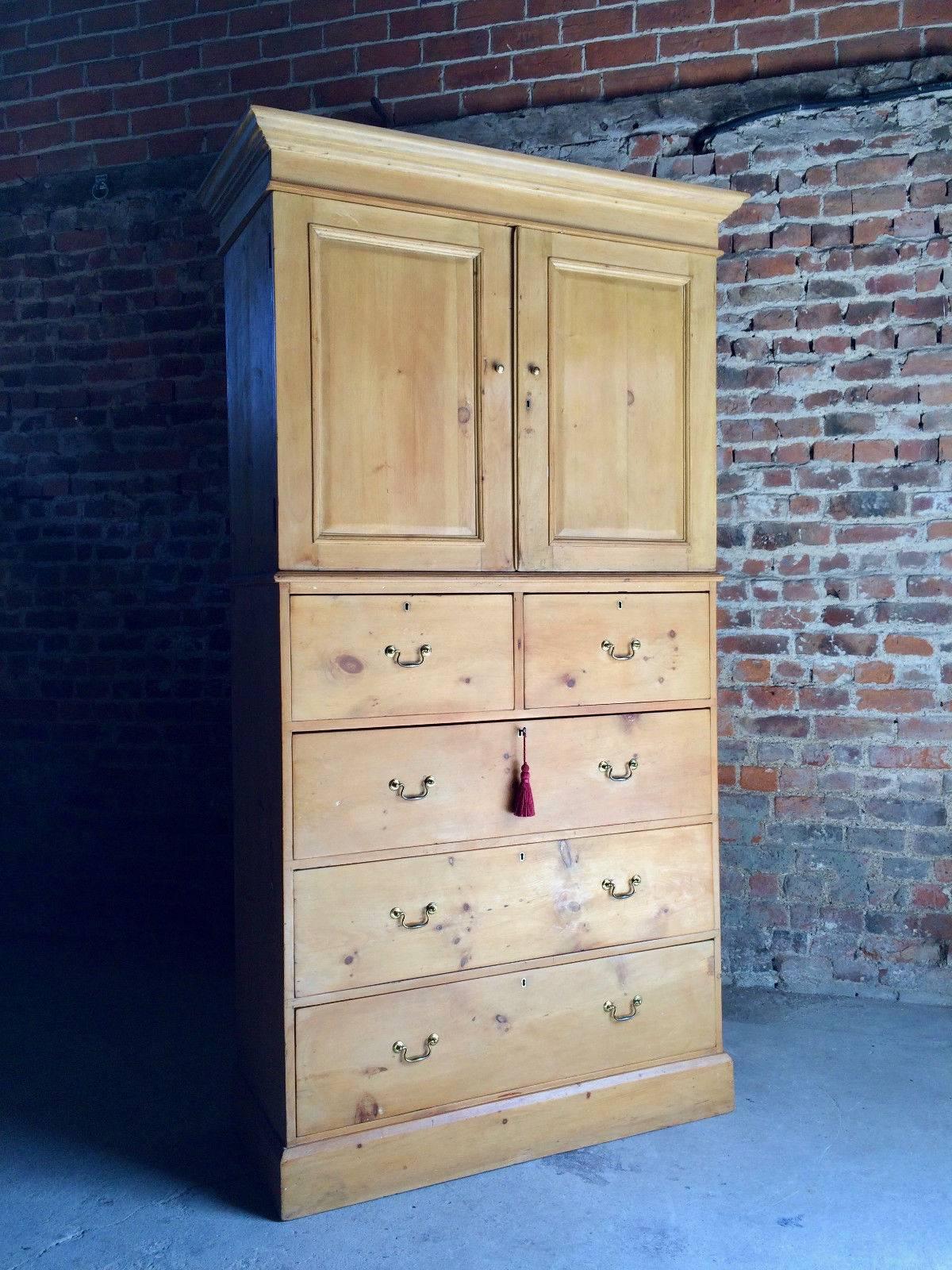 A very tall and beautiful antique 19th century Victorian solid pine linen press over chest, the top with moulded cornice above two panelled doors, enclosing three pull-out sliding trays, the base with two short over three large drawers all with