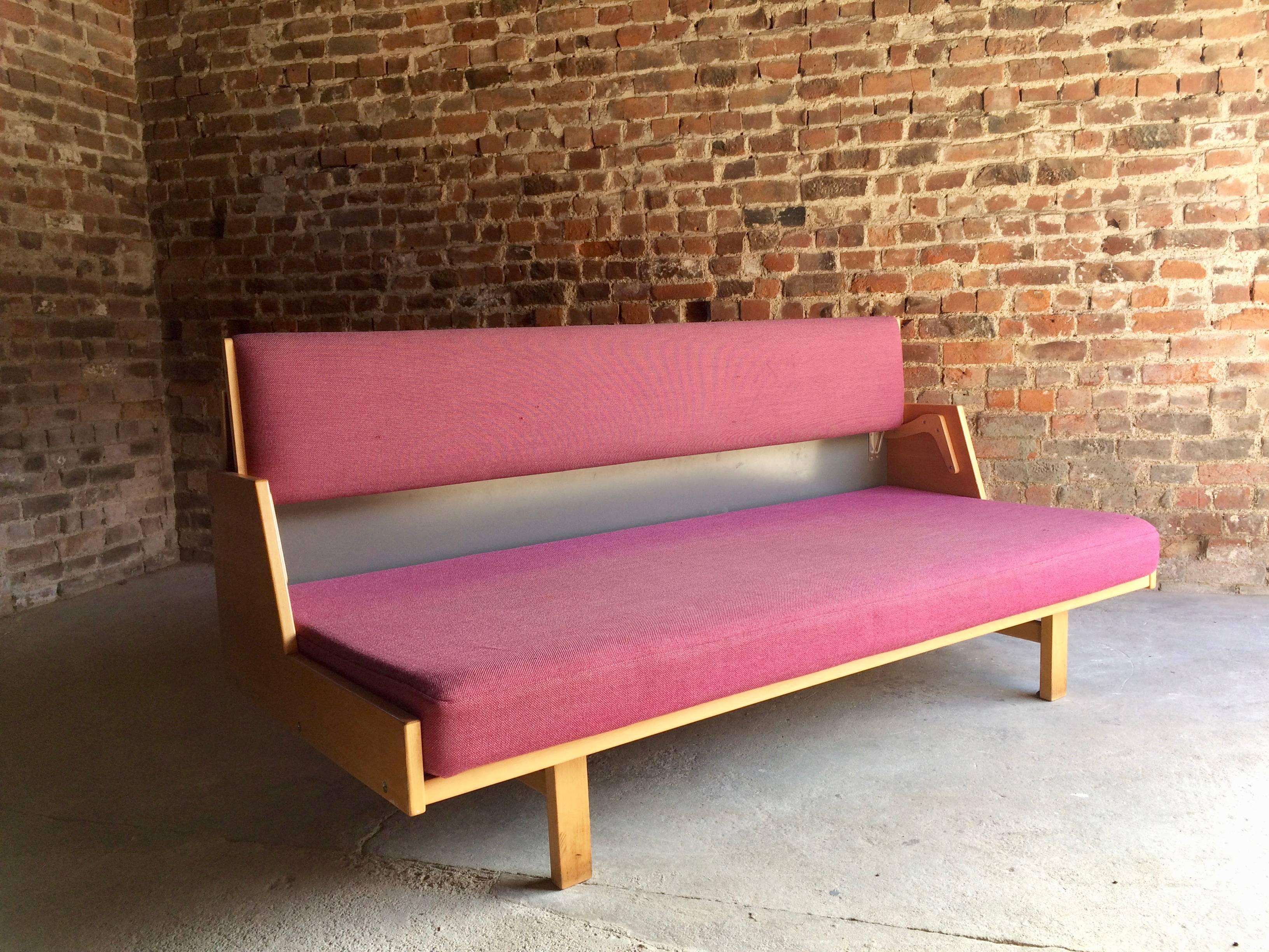 Hans J. Wegner designed in 1954 for GETAMA and produced in Denmark, a beech and upholstered daybed on square feet, the backrest lifting up to allow for use as a twin bed and to reveal a storage area, structurally sound but with wear throughout, may