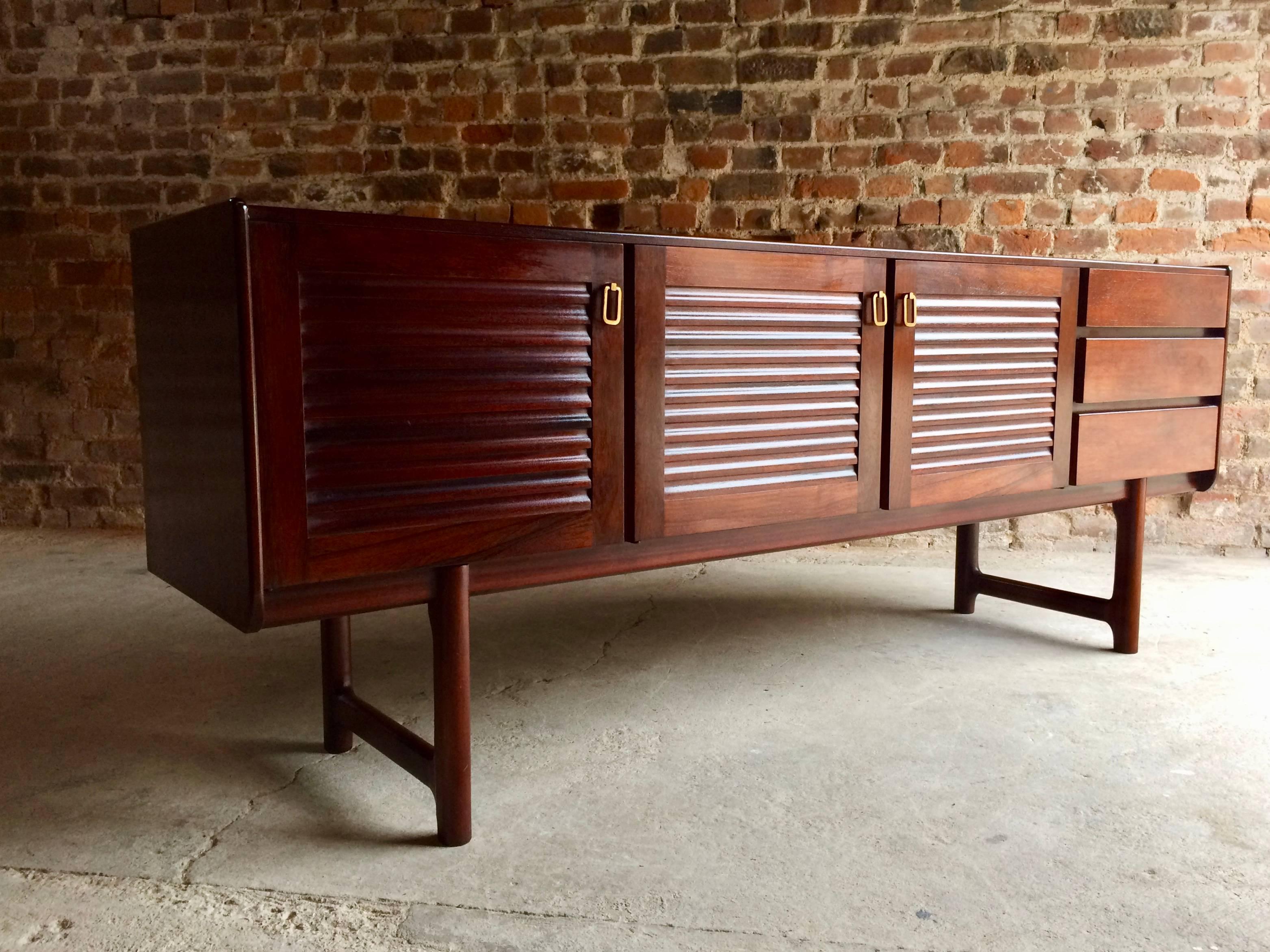 Magnificent Mid-Century A. H. McIntosh & Co of Kirkcaldy rosewood sideboard credenza, circa 1970s, the rectangular top over three louvered cupboard doors with brass handles and shelves within, three drawers to the right side and raised one four