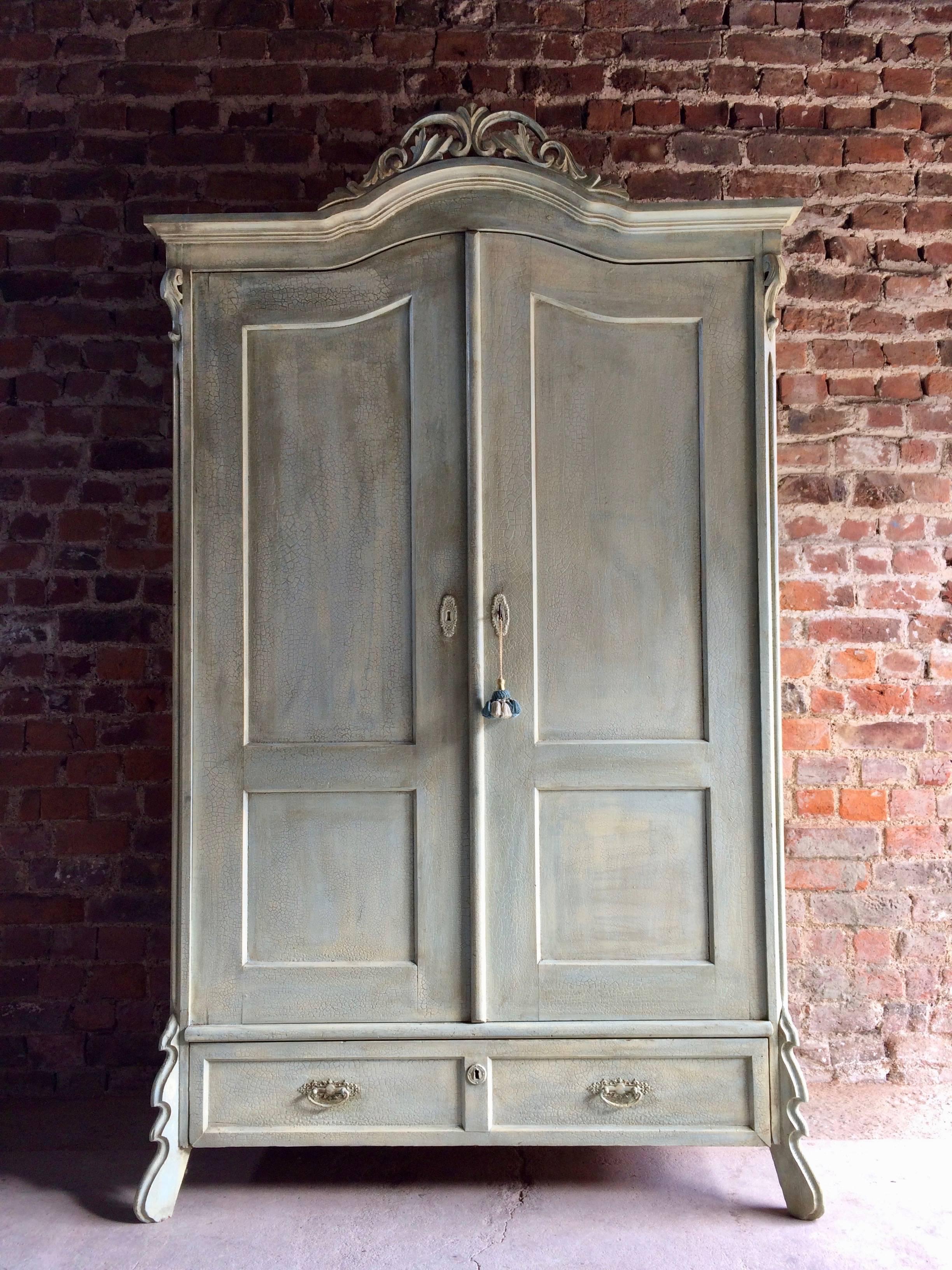 French painted pine armoire, circa 1895, the arched corniced pediment over twin panelled doors, recent brass hanging rail and hanging hooks within, over two drawers and raised on short splayed legs, comes with one working key with tassel, finished