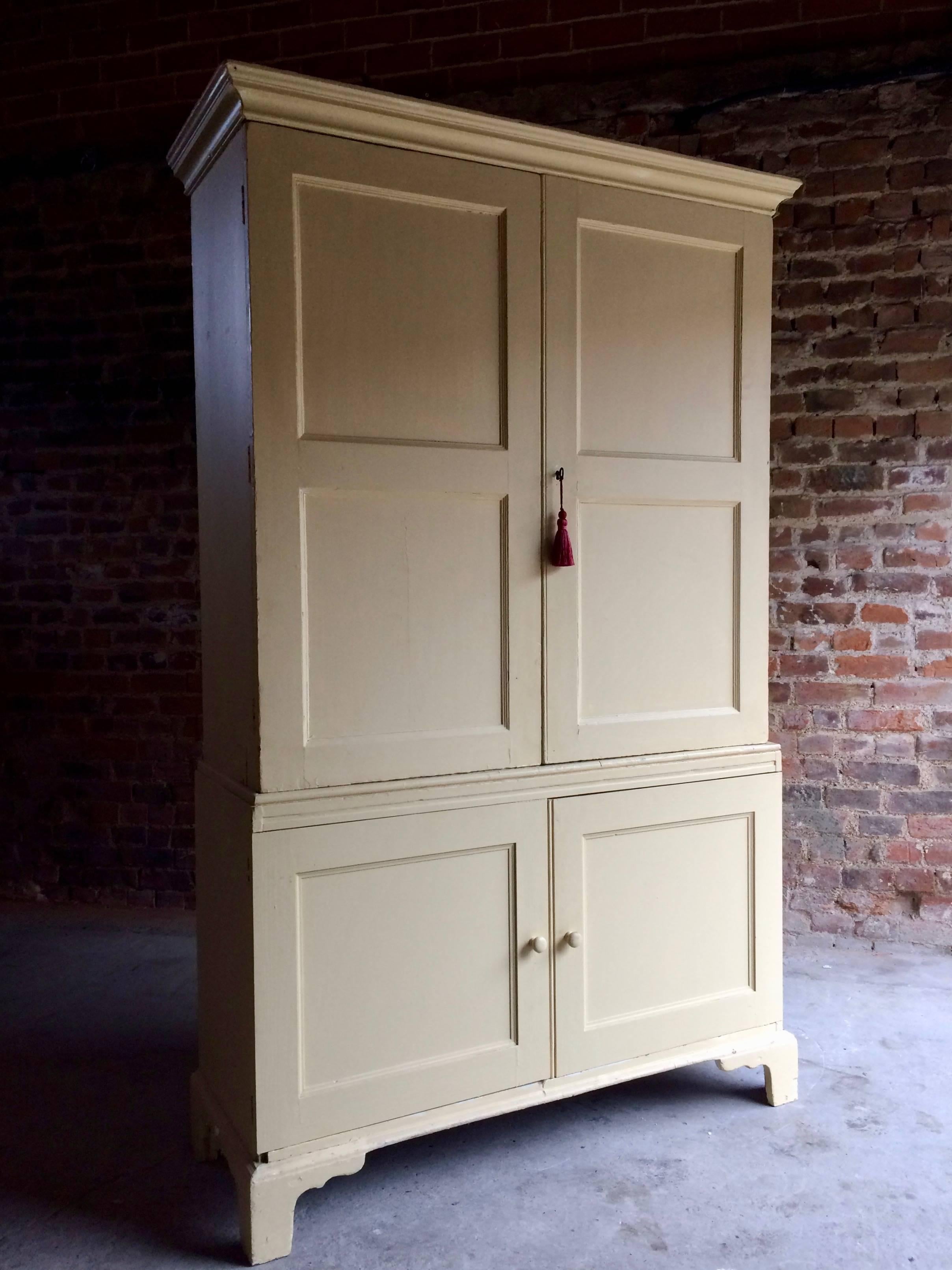 A gorgeous looking antique Georgian pine linen cupboard with later painted 'Buttermilk' finish, circa 1830, the corniced upper section enclosed by a pair of twin panelled doors, the lower section enclosed by a pair of further panelled doors, raised