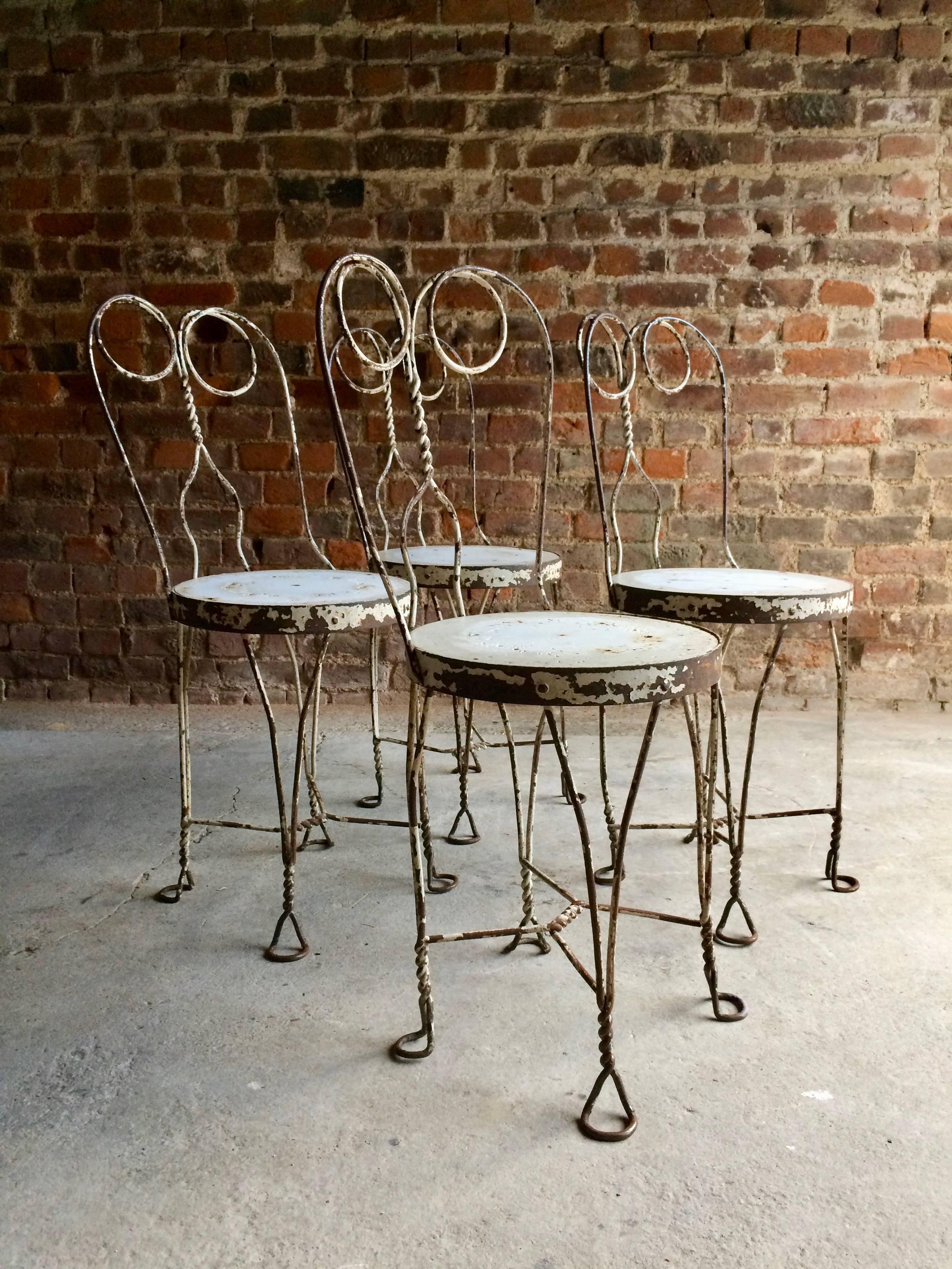 A magnificent early 20th century original French bistro table with four matching chairs circa 1920s, the steel circular table with heavy patination allover with four matching scrolling wrought iron chairs again with heavy patination allover, the set