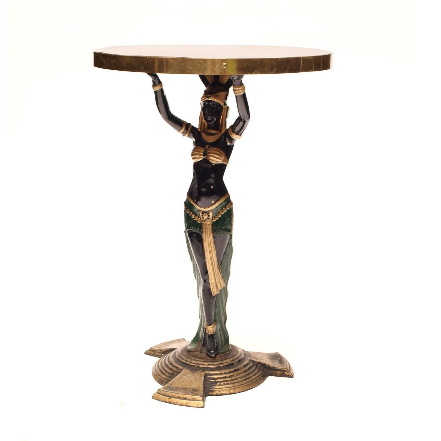 A magnificent and extremely rare pair of early 20th century Art Deco cast iron Egyptian side tables dating to circa 1920s, beautifully painted and gilded female Egyptian maidens supporting circular brass banded table tops, these fabulously naughty