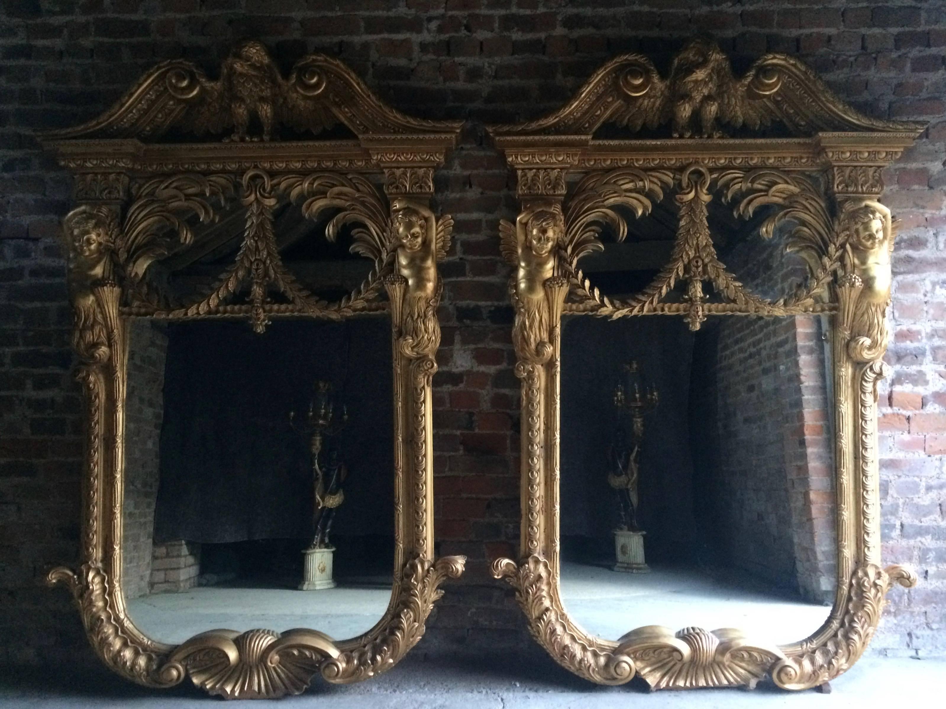 A pair of very large carved French giltwood framed wall mirrors, William Kent design with eagle surmount, broken swan neck pediments flanking putti scrolls and shells.