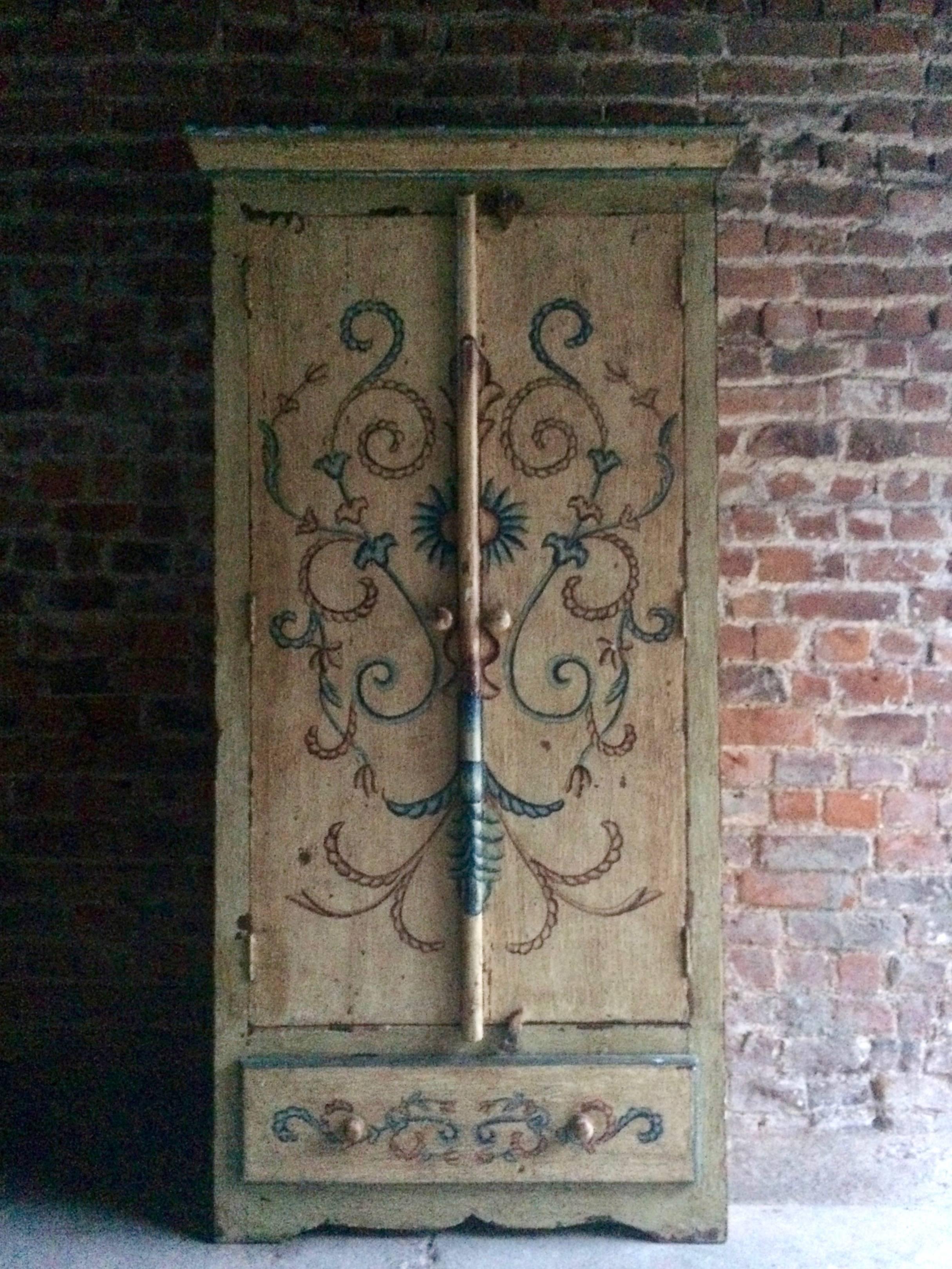 A beautiful early 20th century seriously distressed hand painted cupboard in the French provincial style, the corniced top over two floral painted doors over one long single drawer, raised on a carved shaped apron plinth, the piece with a wonderful