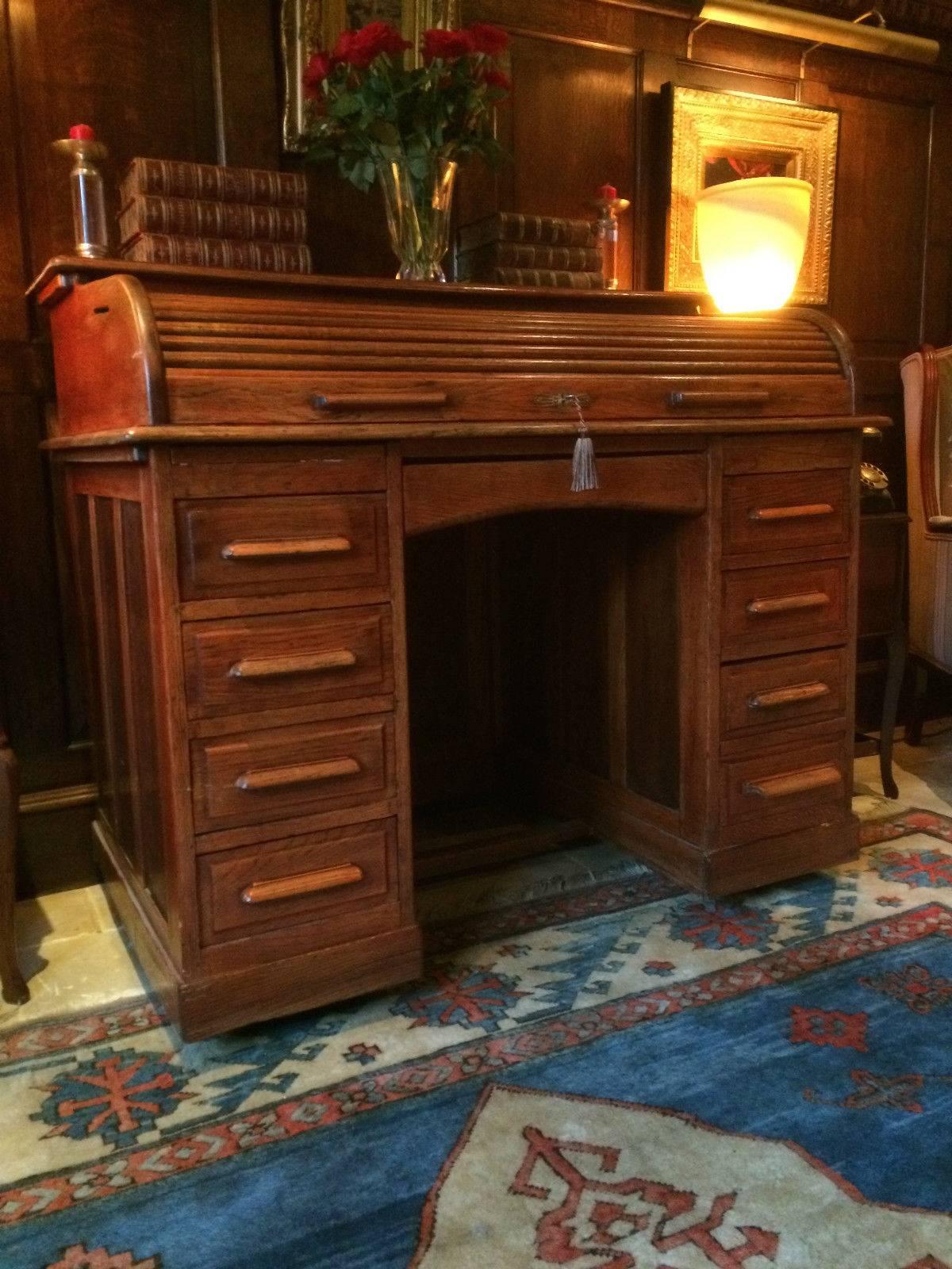 Antique Edwardian solid oak twin pedestal roll top desk, with small drawer and various pigeon holes to the writing area, the desk having a central frieze drawer and seven drawers to the right and left, with lock and working key and tassel, the desk