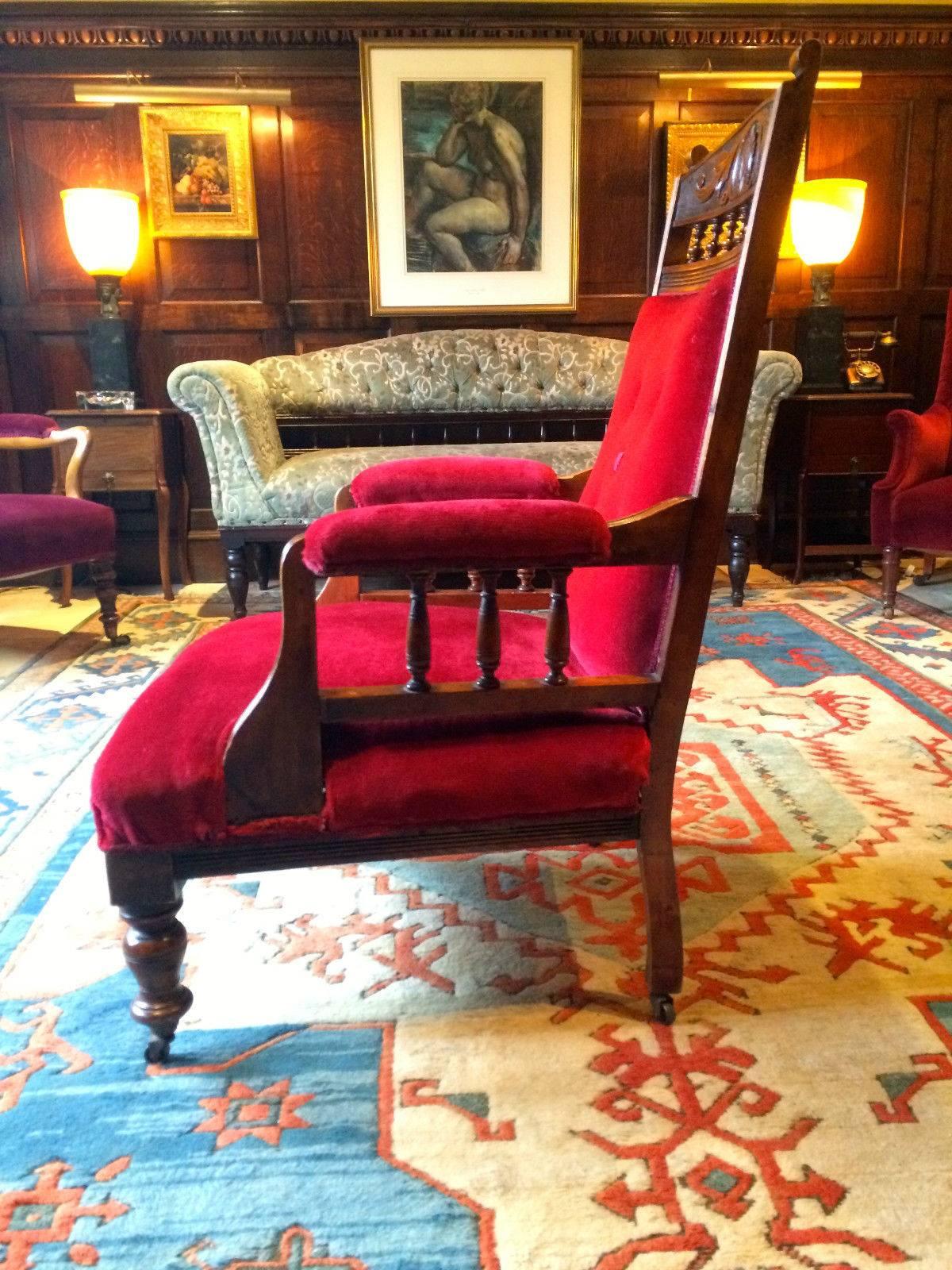 Antique Victorian Mahogany salon armchair with overstuffed arms, back and seat, spindles to arms and back with carved decoration, finished in a lush ‘Scarlet Red’ velvet material, standing on turned front legs and raised on brass casters, there is