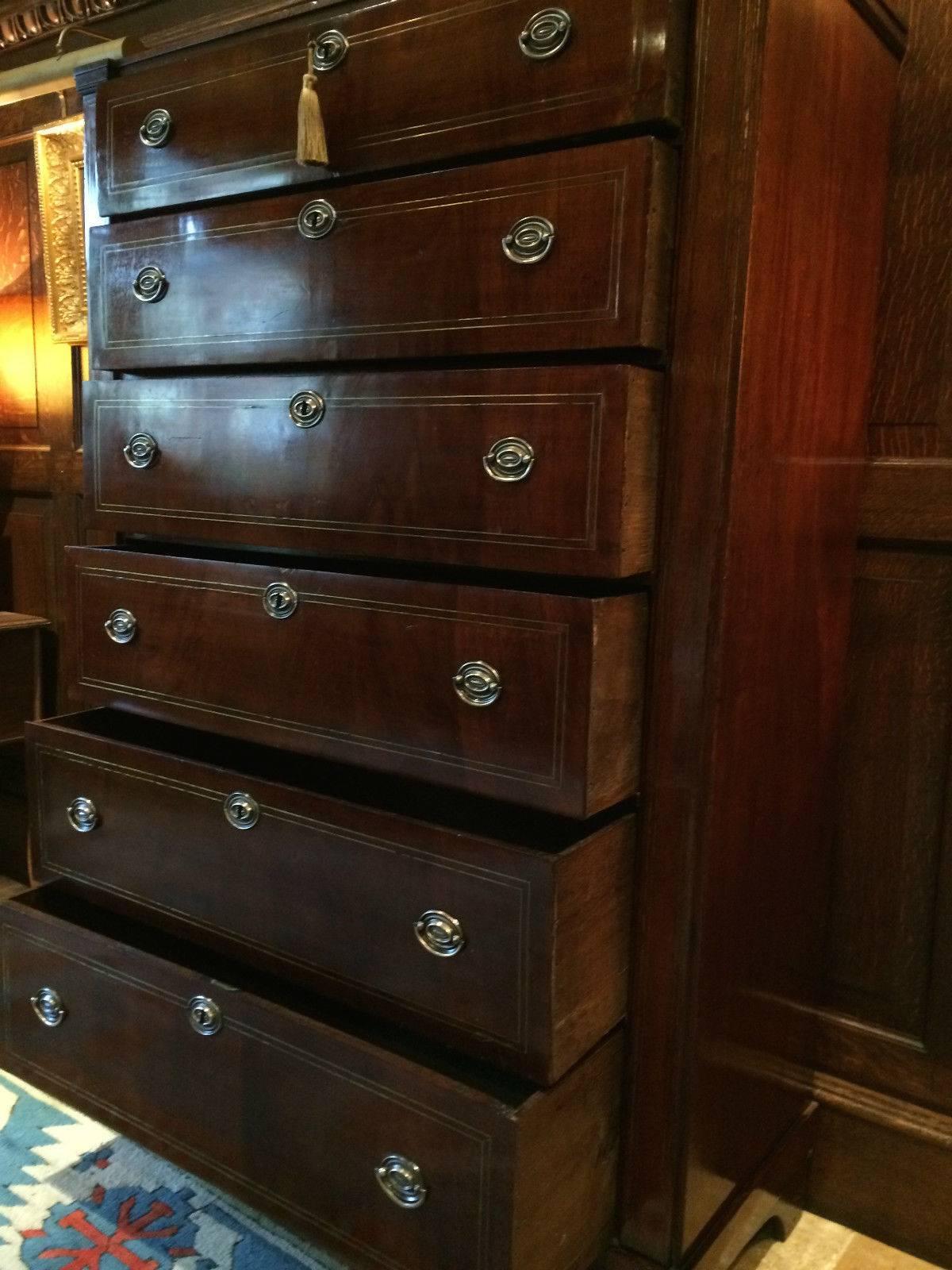 A 19th century antique George III flame fronted mahogany ‘tallboy' chest of drawers dresser, rectangular top over six brass strung inlay to the front of graduated drawers, original oval brass drop handles and brass escutcheons, comes with one