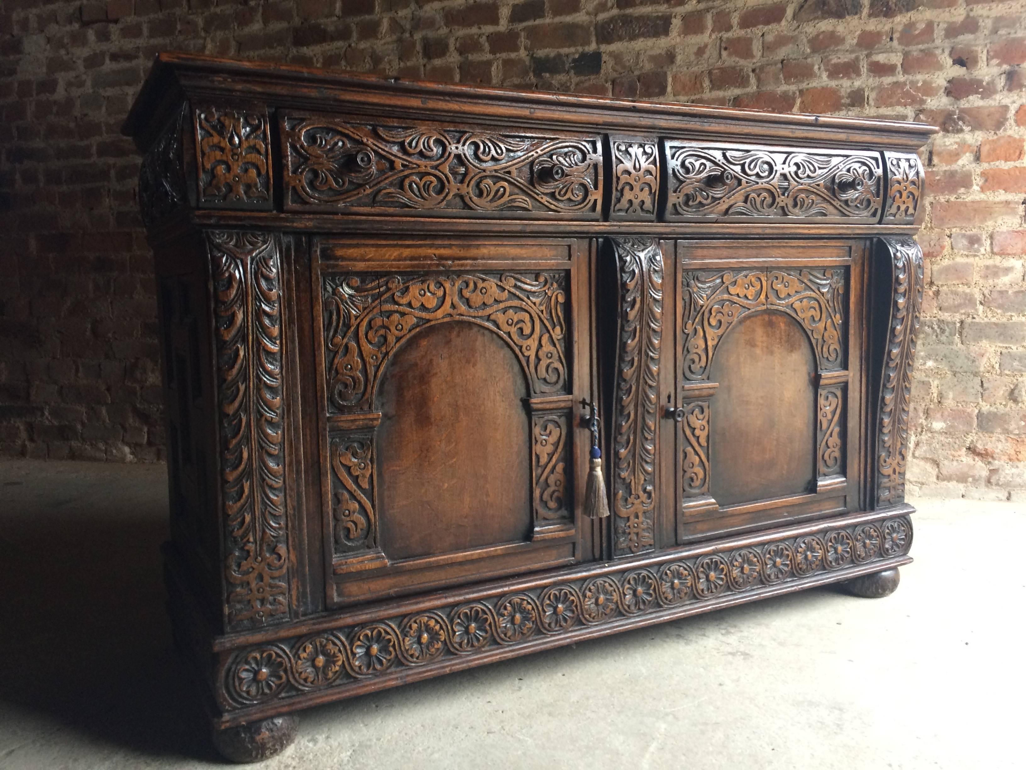 A beautiful, heavily carved antique 19th century solid oak sideboard buffet circa 1850, the rectangular plankled top over two frieze drawers above a pair of cupboard doors both having shelves within, profuse carvings allover, comes with one working