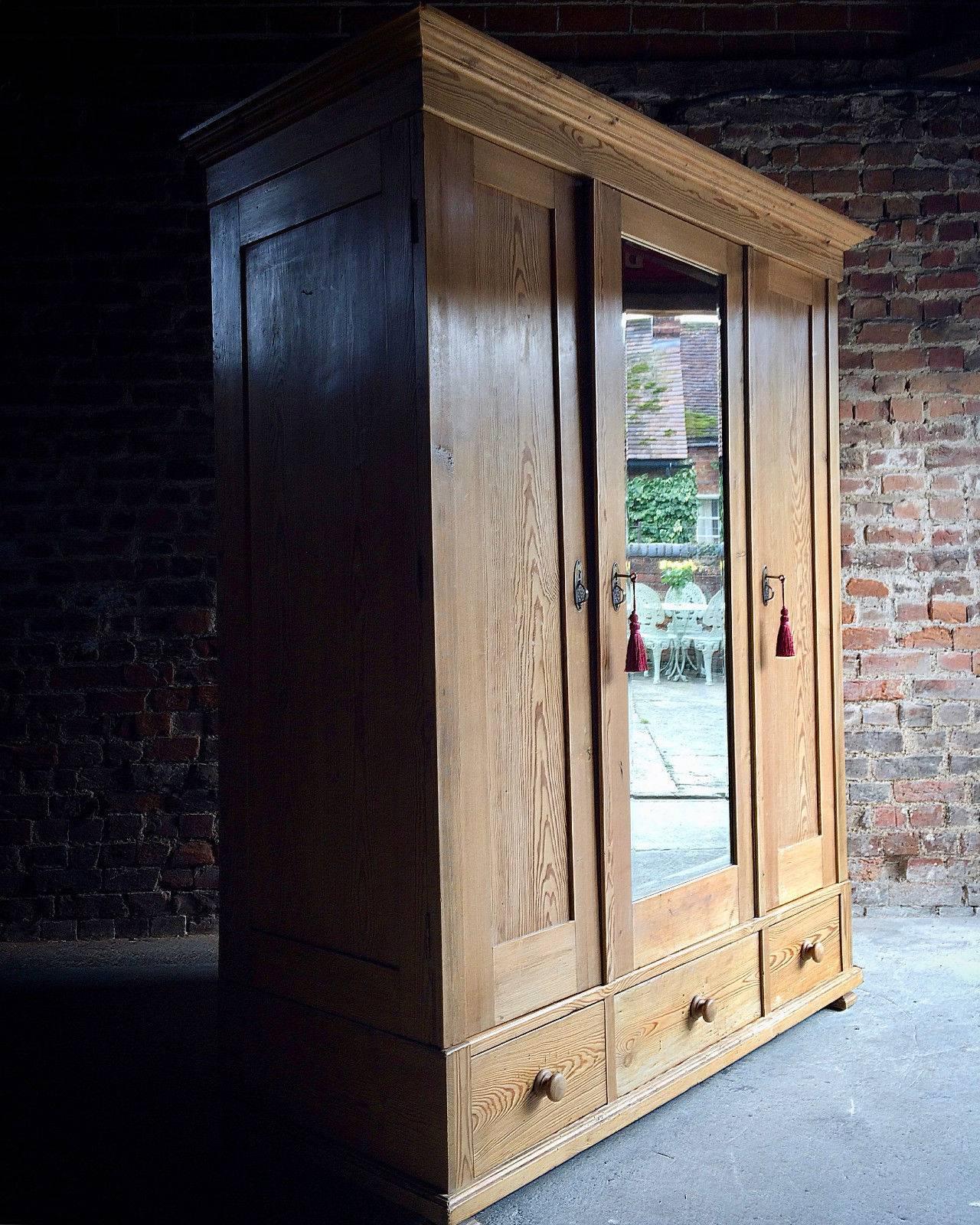 A beautiful antique farmhouse style French solid pine triple aspect wardrobe armoire, corniced top over three doors one with full length mirror, hanging rail to the left side of the robe and four shelves to the right, above three pull-out drawers,