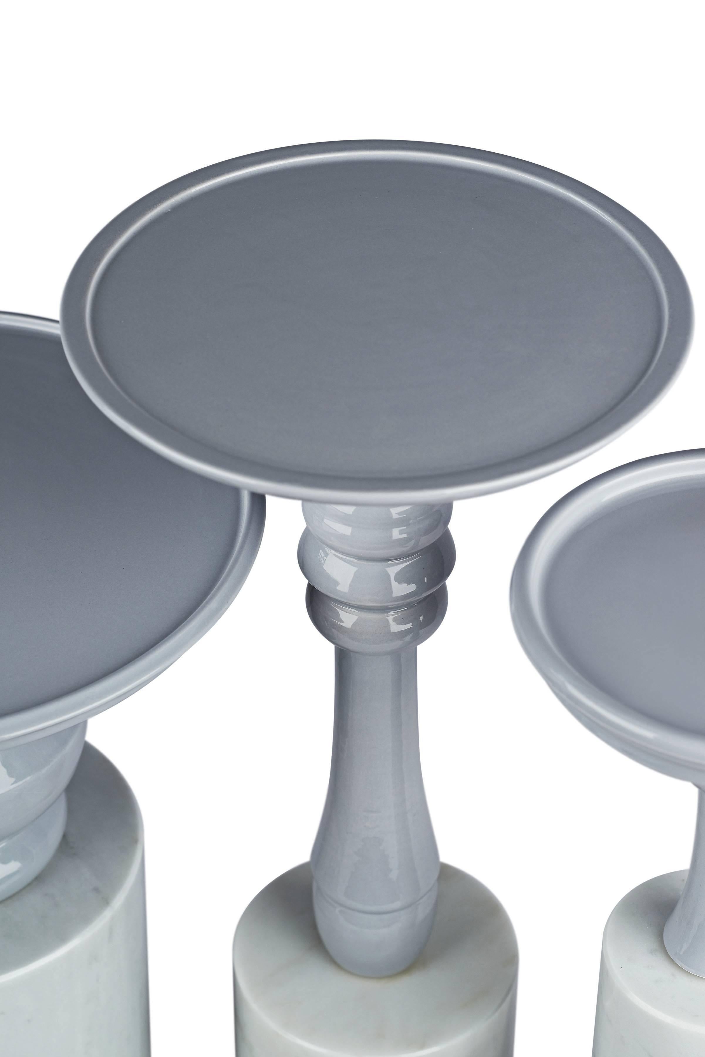 This set of four small tables are made of hand-glazed ceramic and Carrara marble. The overall dimensions of the four tables when placed together measure approximately 20” H x 28 3/4” W x 28 3/4” D. Each individual table's measurements vary from 14