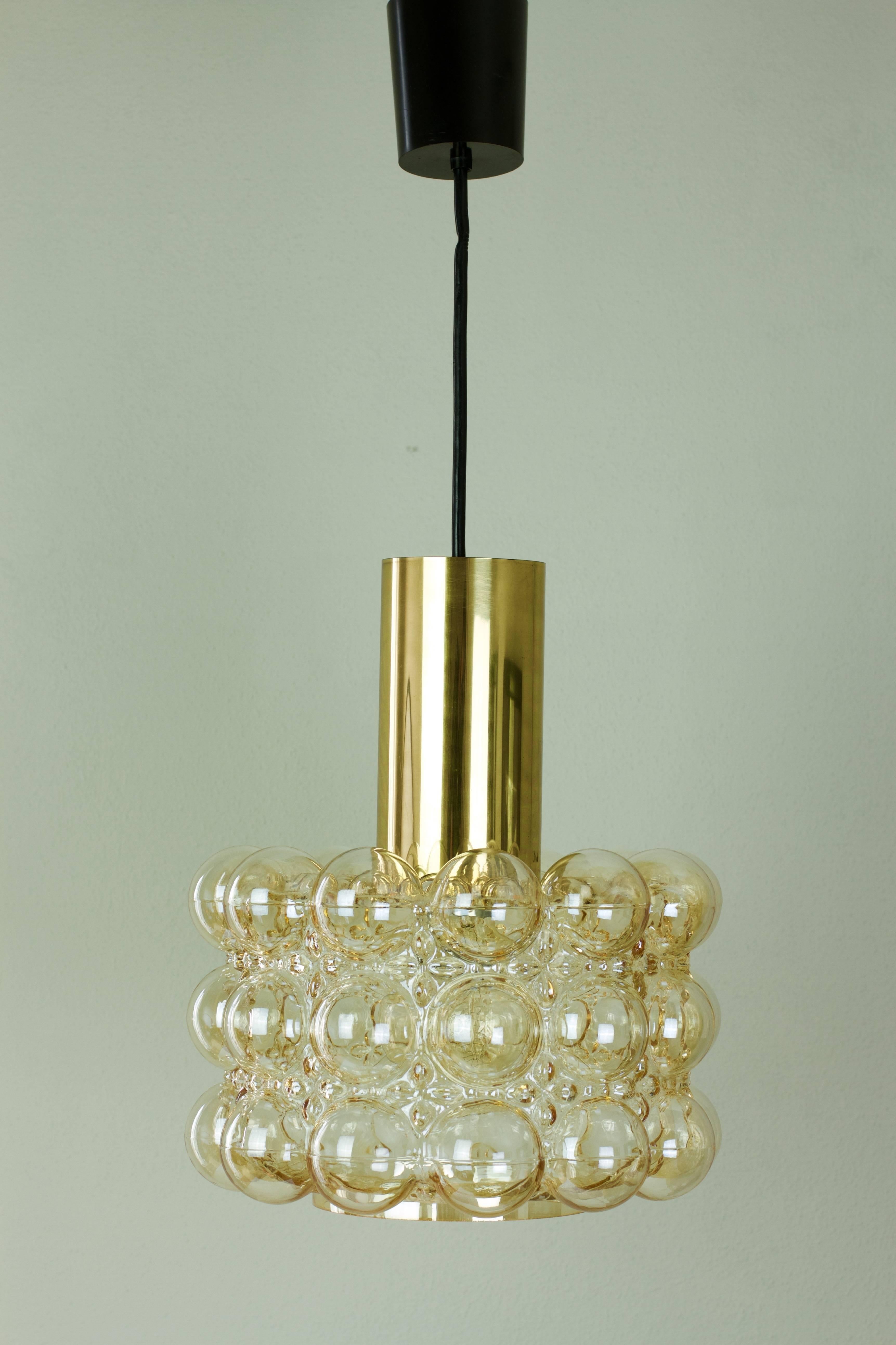 Late 1960s bubble glass ceiling pendent light designed by Helena Tynell for Glashütte Limburg. The light features a beautiful lampshade made from amber or champagne colored / coloured glass with a polished brass cylinder on top.

This, German