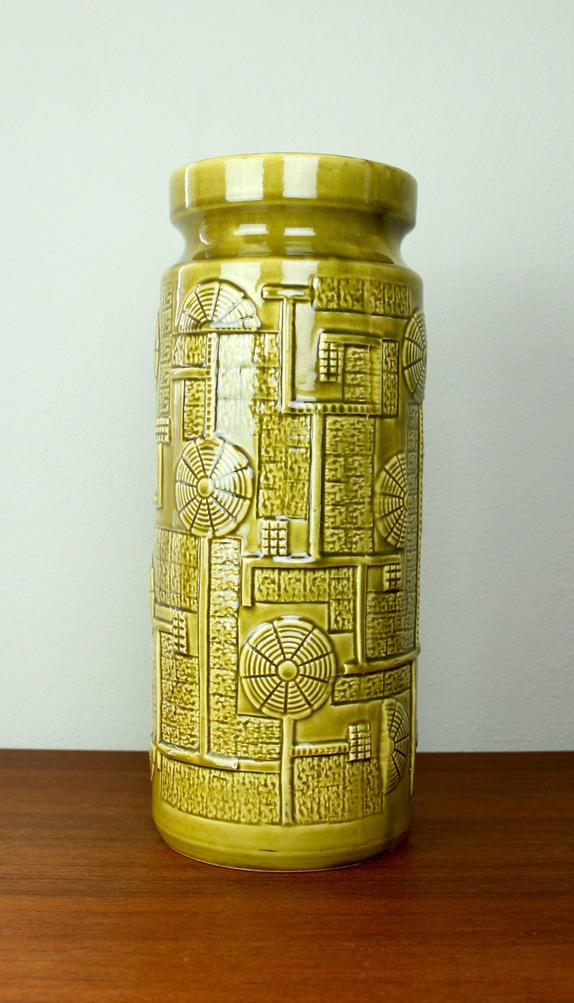 Beautiful tall vase from the 'Narvik' range designed by Bodo Mans and produced by Bay Keramik in the early to mid-1970s. The Futuristic relief pattern, captured in a mustard yellow or green, looks somehow Aztec like whilst maintaining a feeling of