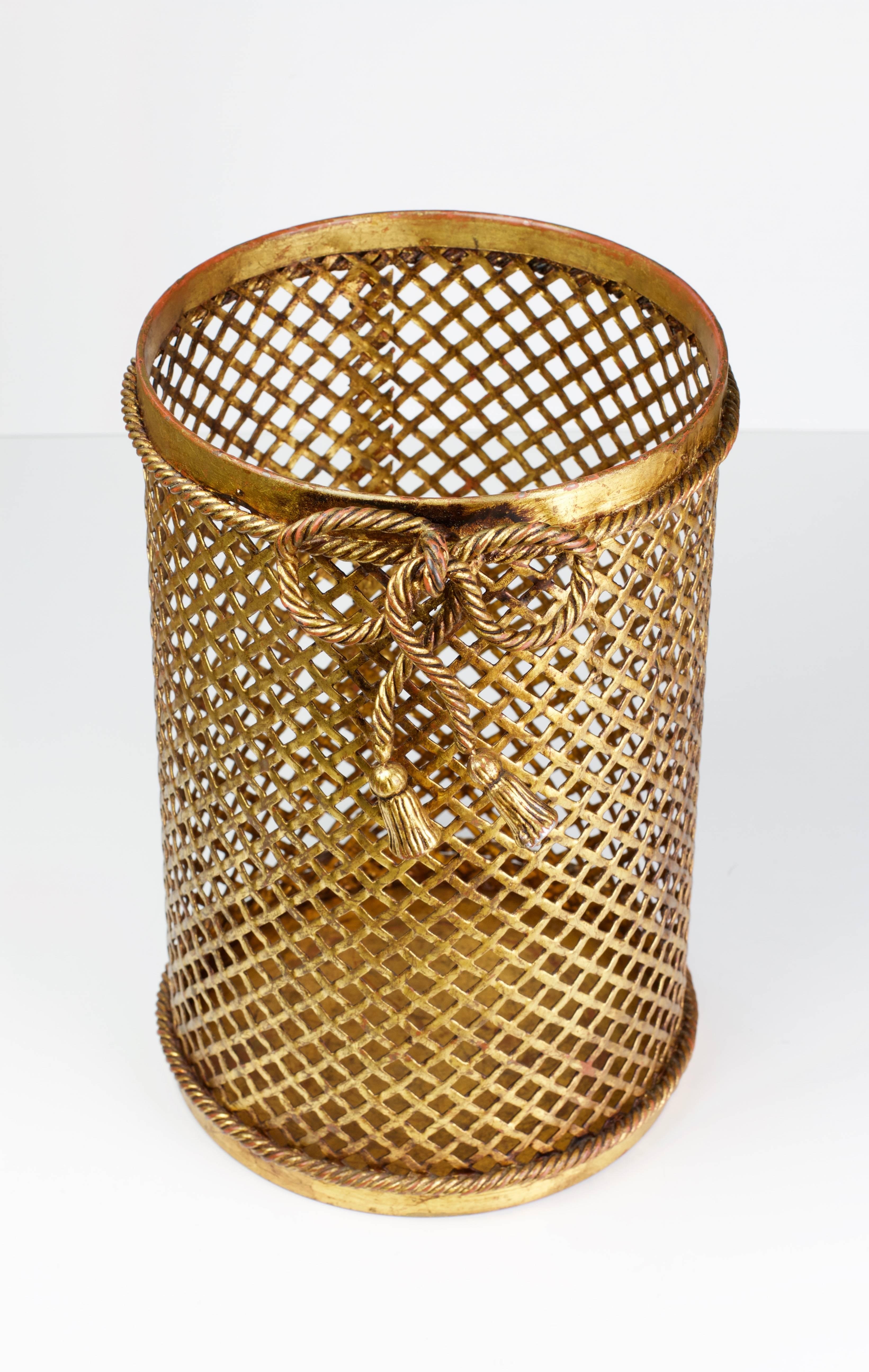Stunning & vintage gold / gilt / gilded Hollywood Regency style trash can / bin / waste paper basket made in Italy, circa 1950. The perforated lattice patterned metalwork with bent rope and tassel details finishes the piece perfectly. Quite rare to