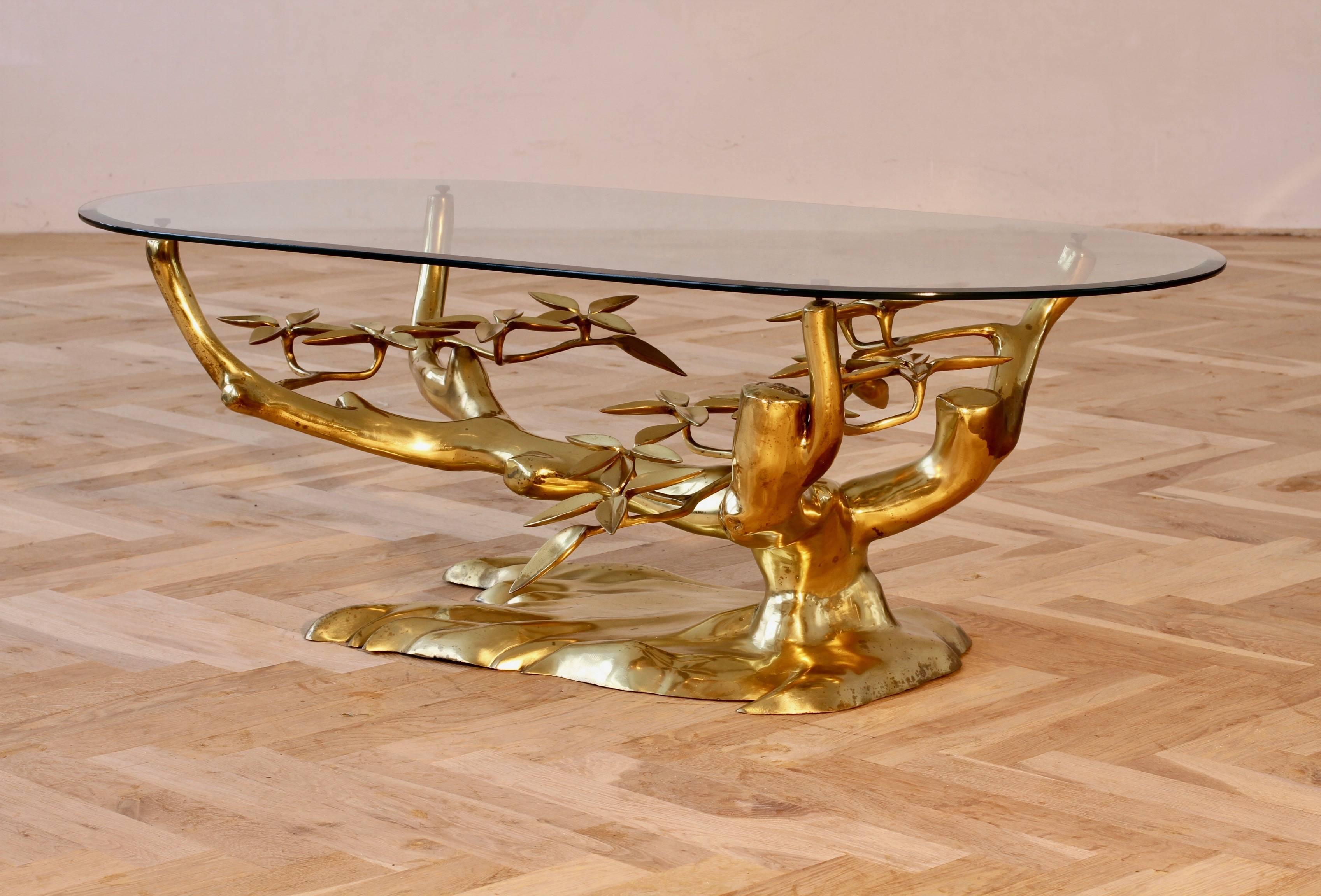 This wonderful and whimsical Willy Daro inspired table, cast in brass, takes on the form of a 'Bonsai' tree with the very stylised flower petals, while the brass branches hold a beveled edged glass table top. 

Produced in Belgium, circa 1970, this