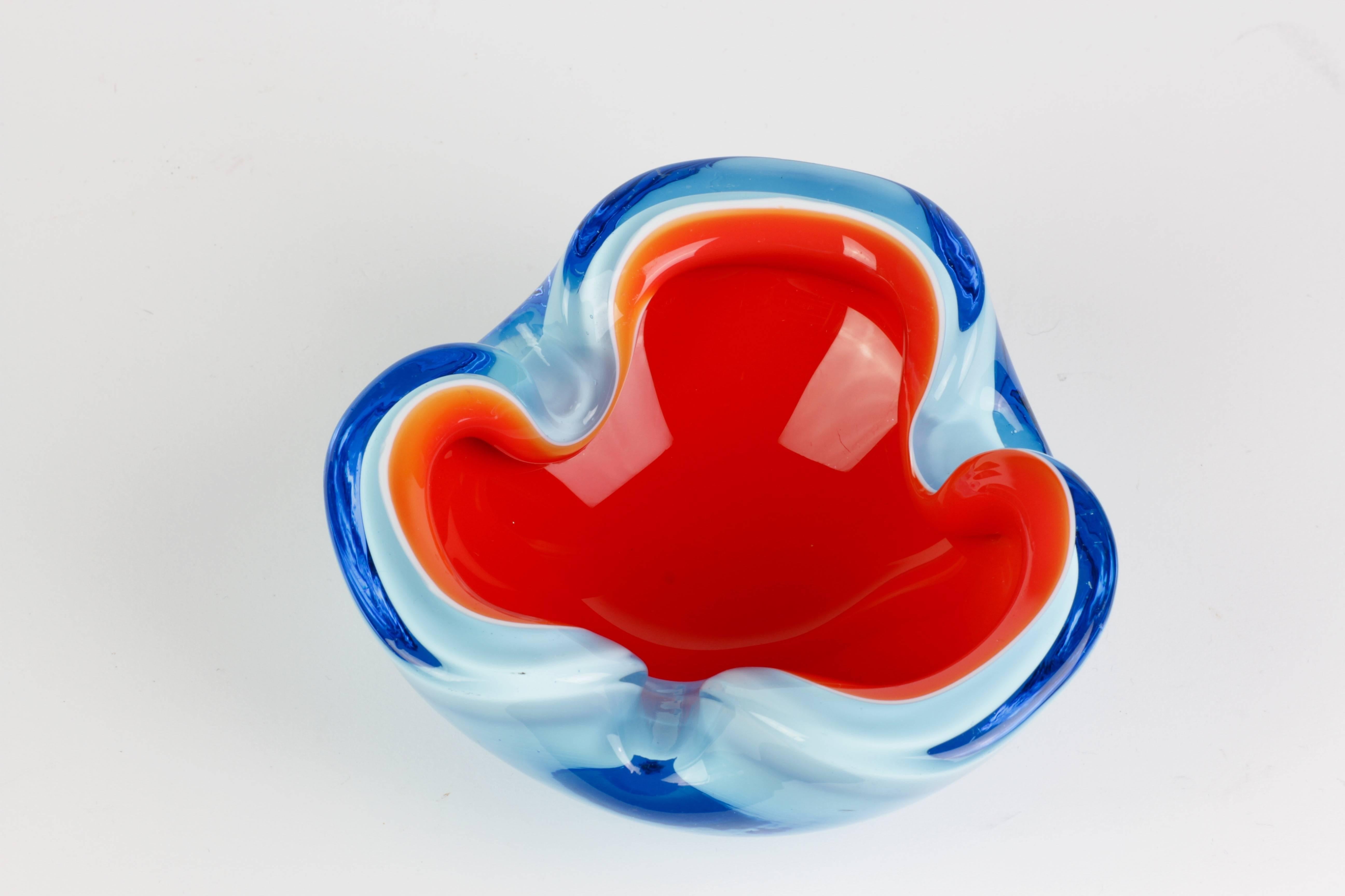 A wonderful and mesmerising Murano bowl or ashtray attributed to Cenedese, circa 1970. We just love the bright, vibrant colors of ocean blue clear glass over sky blue over white over vibrant orange. 

It's quite the jellybean array of colours and