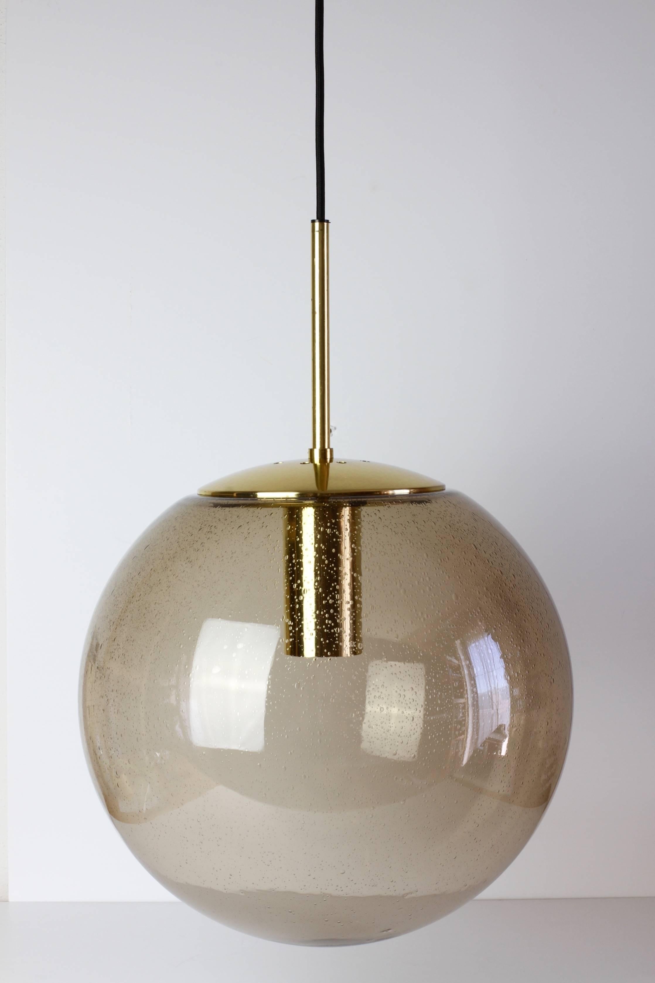 Large Mid-Century hanging pendant lights by Glashütte Limburg. Made in the late 1960s throughout to the late 1970s, this gorgeous light features a mouth blown smoked glass globe containing many tiny bubbles resembling water droplets. 

All hardware