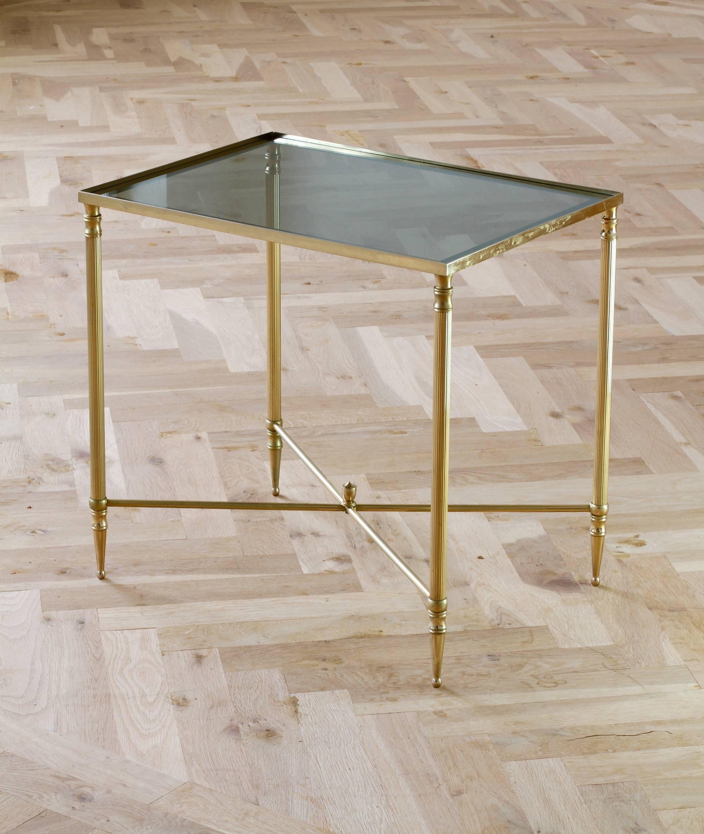A wonderful tall side or end table attributed to Maison Jansen, circa 1970. Made from solid brass in the neoclassical style and featuring a dark toned smoked glass tabletop with a mirrored border. This delightful table, not dissimilar to designs by
