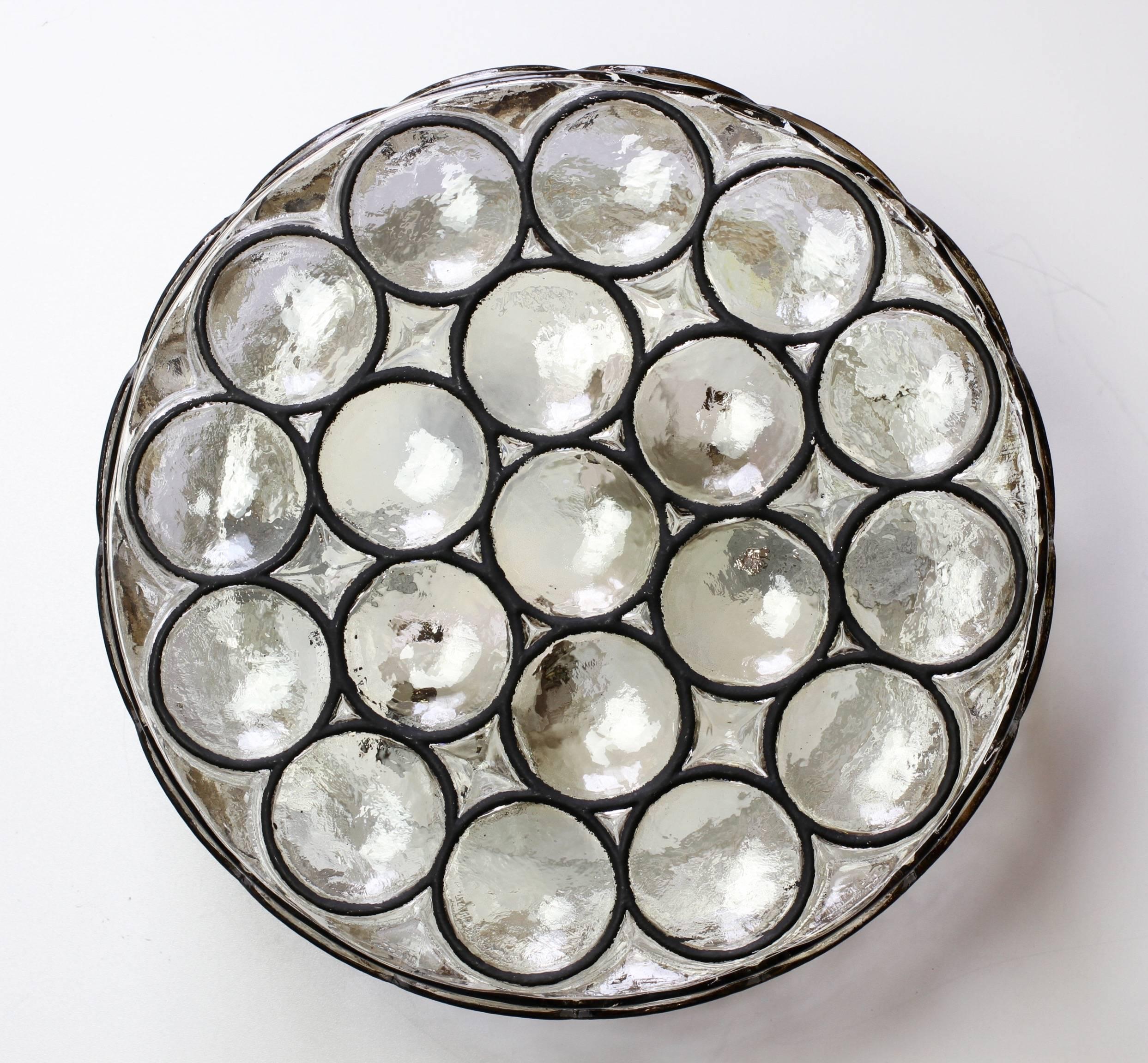 A single large double socketed circular iron and glass flush mount lights / sconces by Glashütte Limburg, Germany, circa 1965. Featuring thick heavy blown glass with concaved round "Iron" rings which cast a wonderful light across a wall or