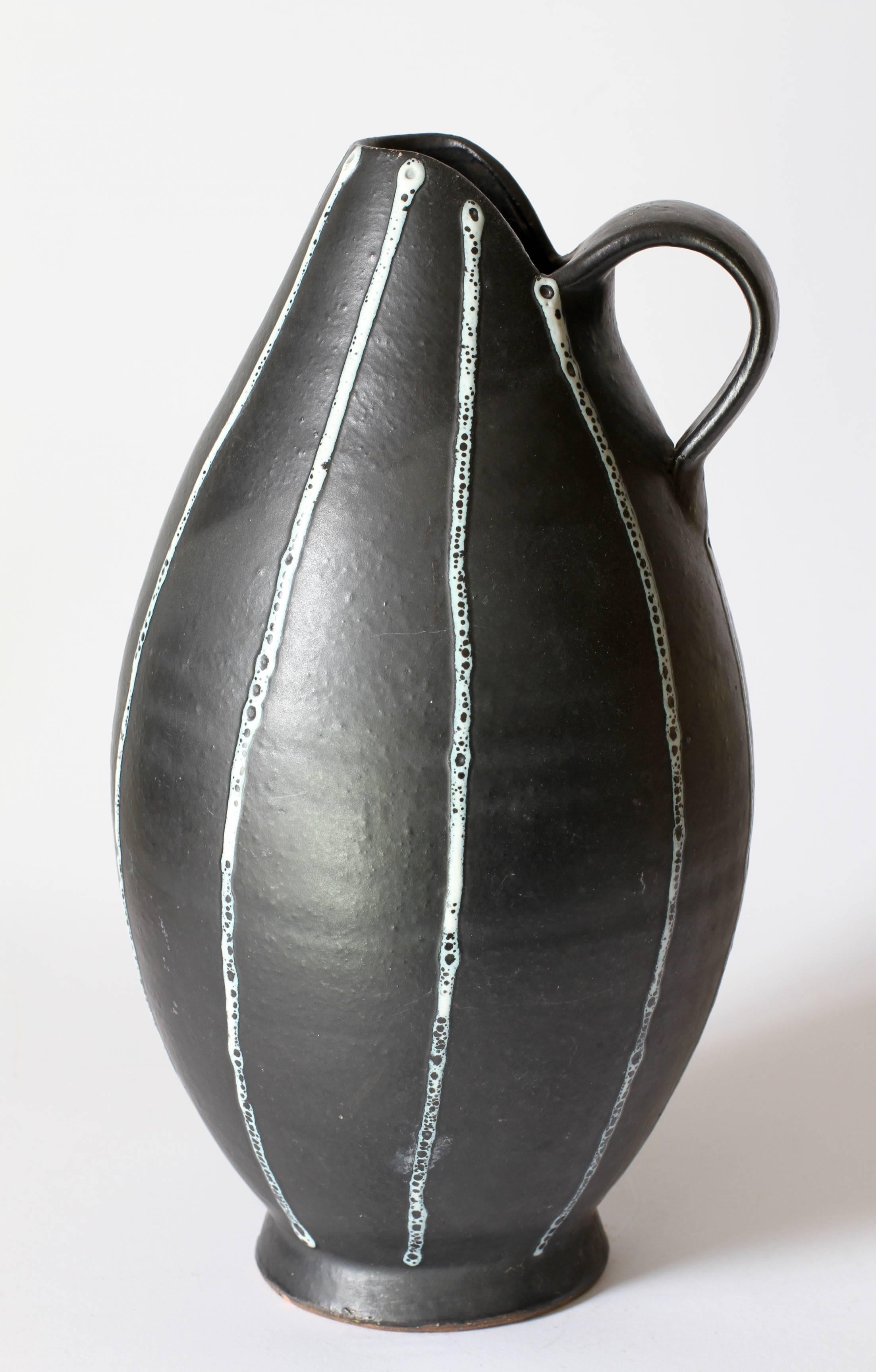 This elegant jug or pitcher was hand thrown by an unknown studio potter, circa 1950-1959. It is certainly of European origin and most likely German made as it has very similar glaze techniques to those found on vases from the West German Pottery