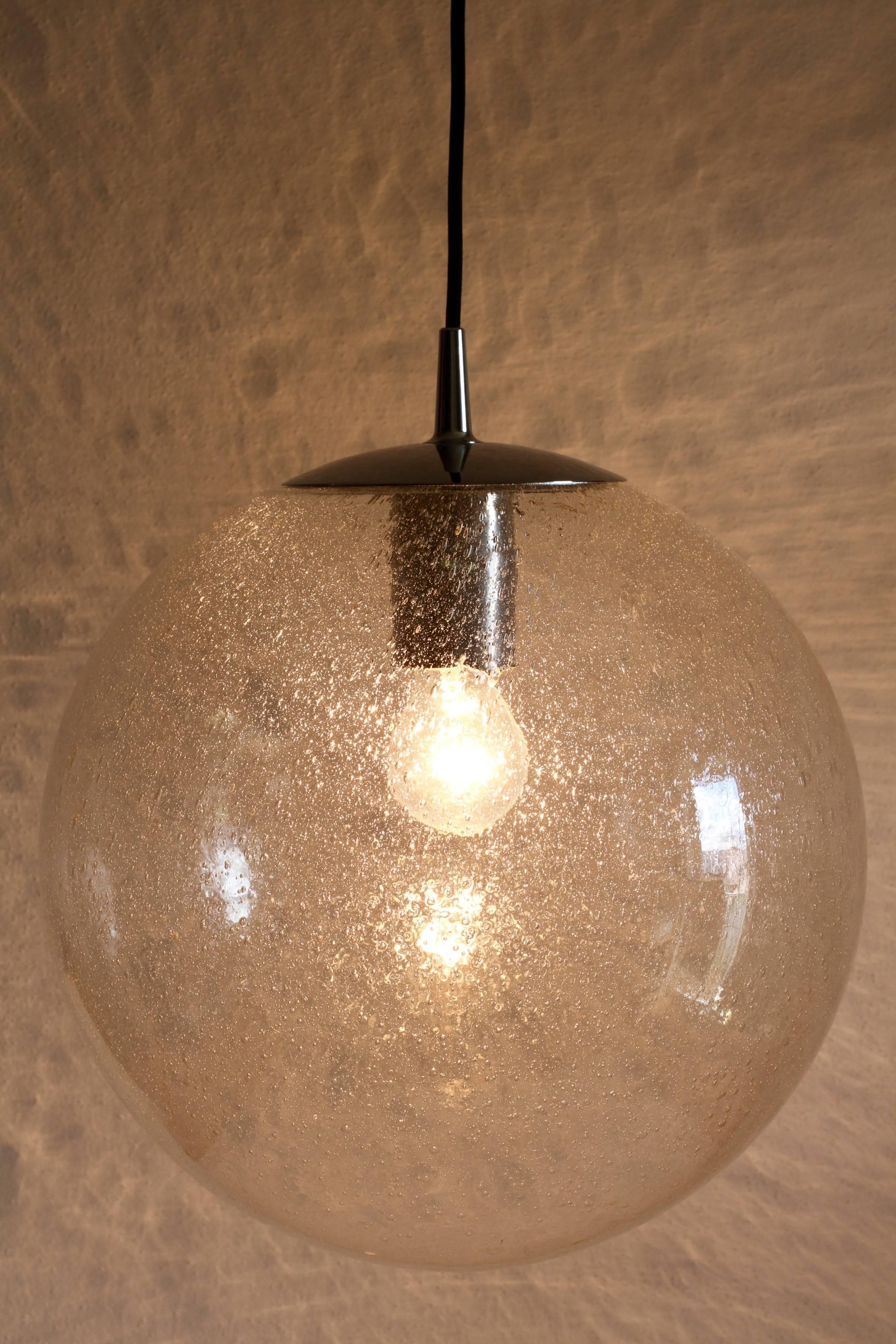 One of a set of four large Mid-Century hanging pendant lights by renowned German lighting manufacturer Peill & Putzler. Made in the early 1970s, these gorgeous light fixtures feature a mouth blown clear 'bubble' or 'Pulegoso' glass globe containing