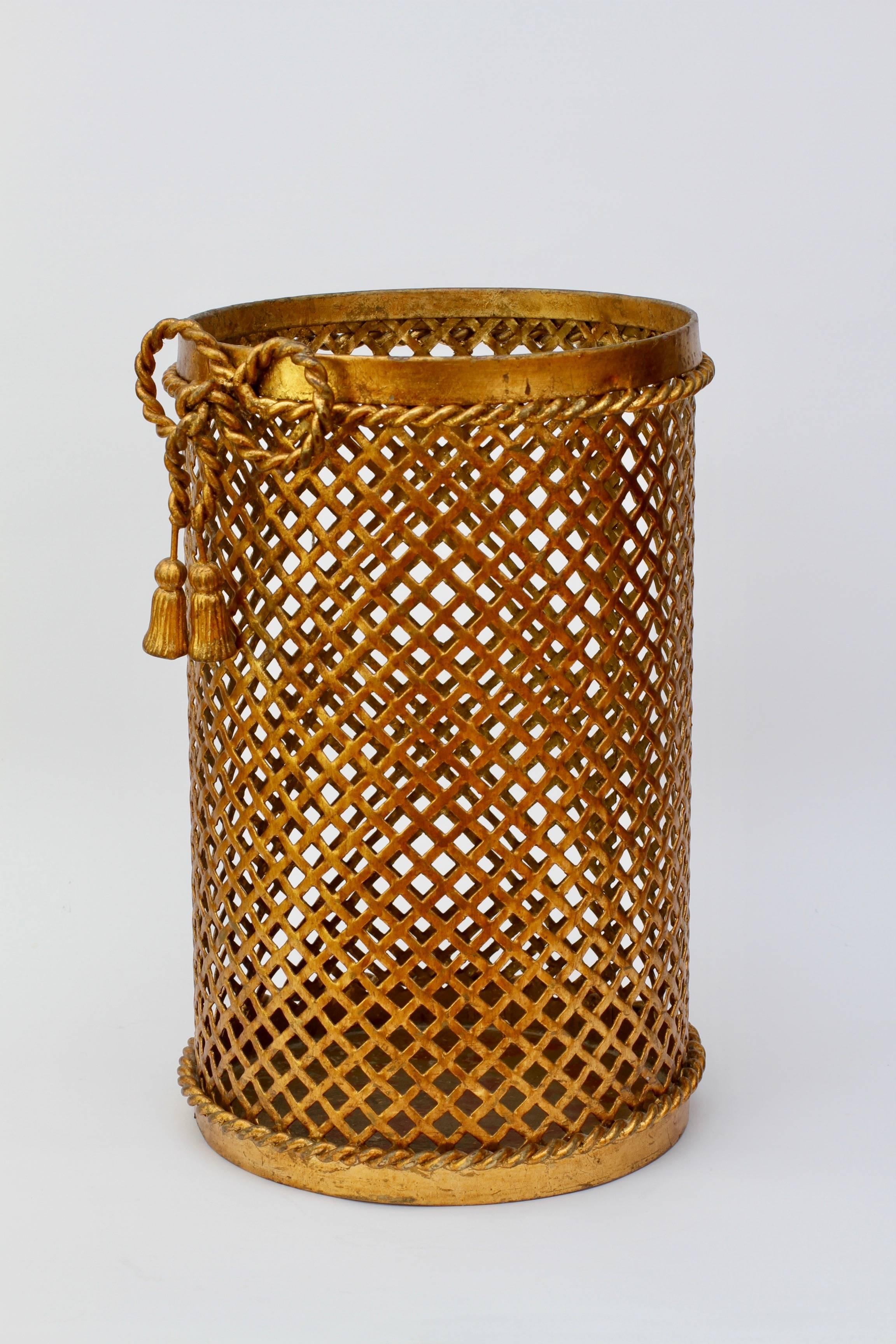 Stunning and vintage gold / gilt / gilded Hollywood Regency style trash can / bin / waste paper basket made in Italy, circa 1950. The perforated lattice patterned metalwork with bent rope and tassel details finishes the piece perfectly. Quite rare