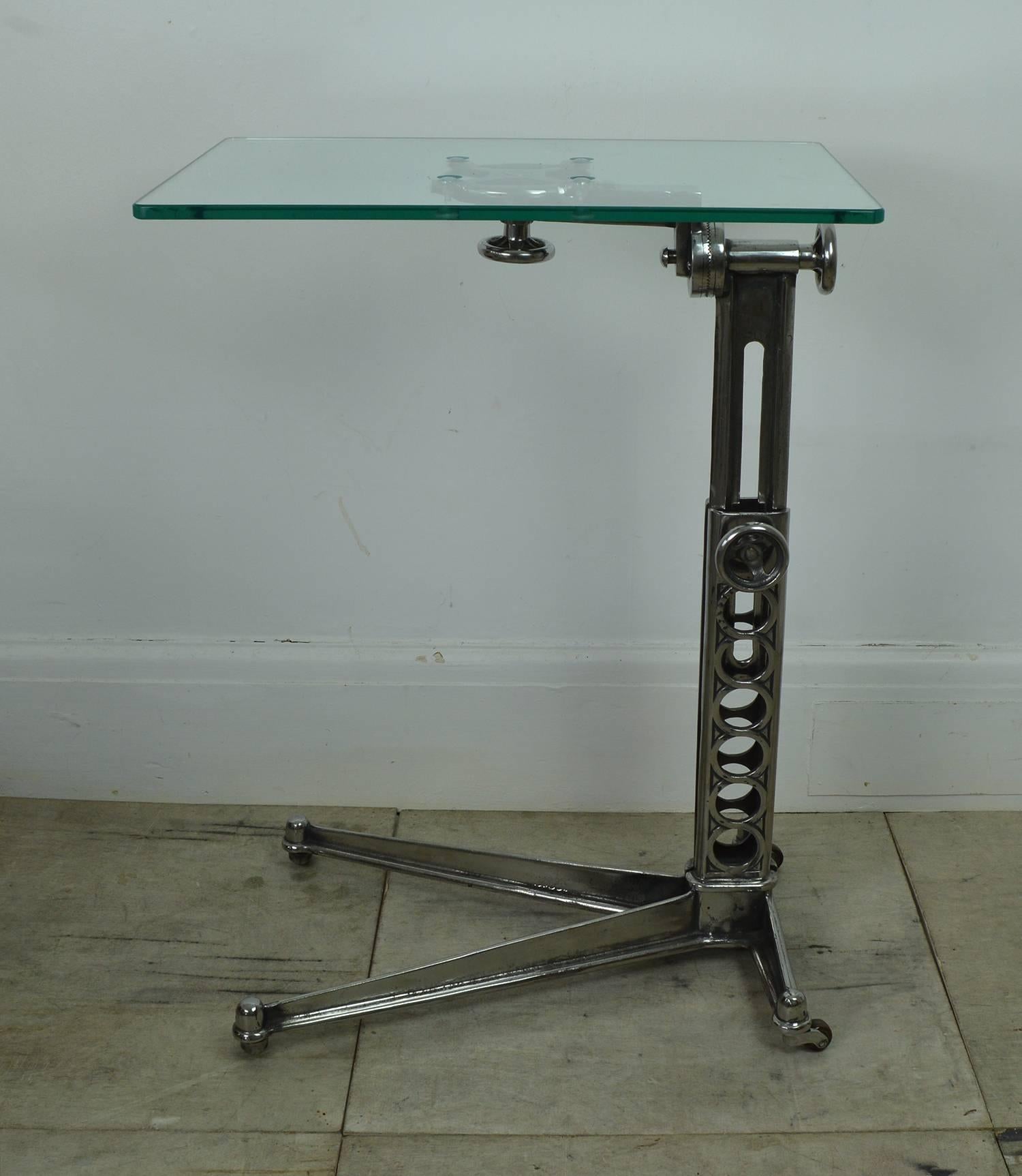 Stylish side or work table with an elegant Industrial look.

Made of cast iron and steel (recently highly polished) with a new toughened glass top.

Original pot castors.

The top is adjustable to a maximum of 37 inches (95 cm). It is easily