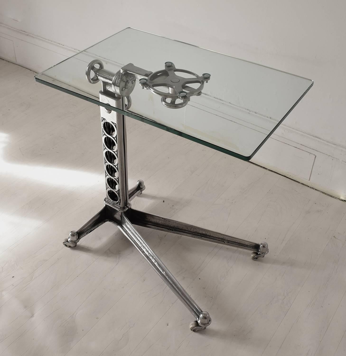 Stylish side or work table with an elegant Industrial look.

Made of polished cast iron with a new toughened glass top.

Original white pot castors.

The top is adjustable to a maximum of 37 inches.

It is easily adjusted by loosening the