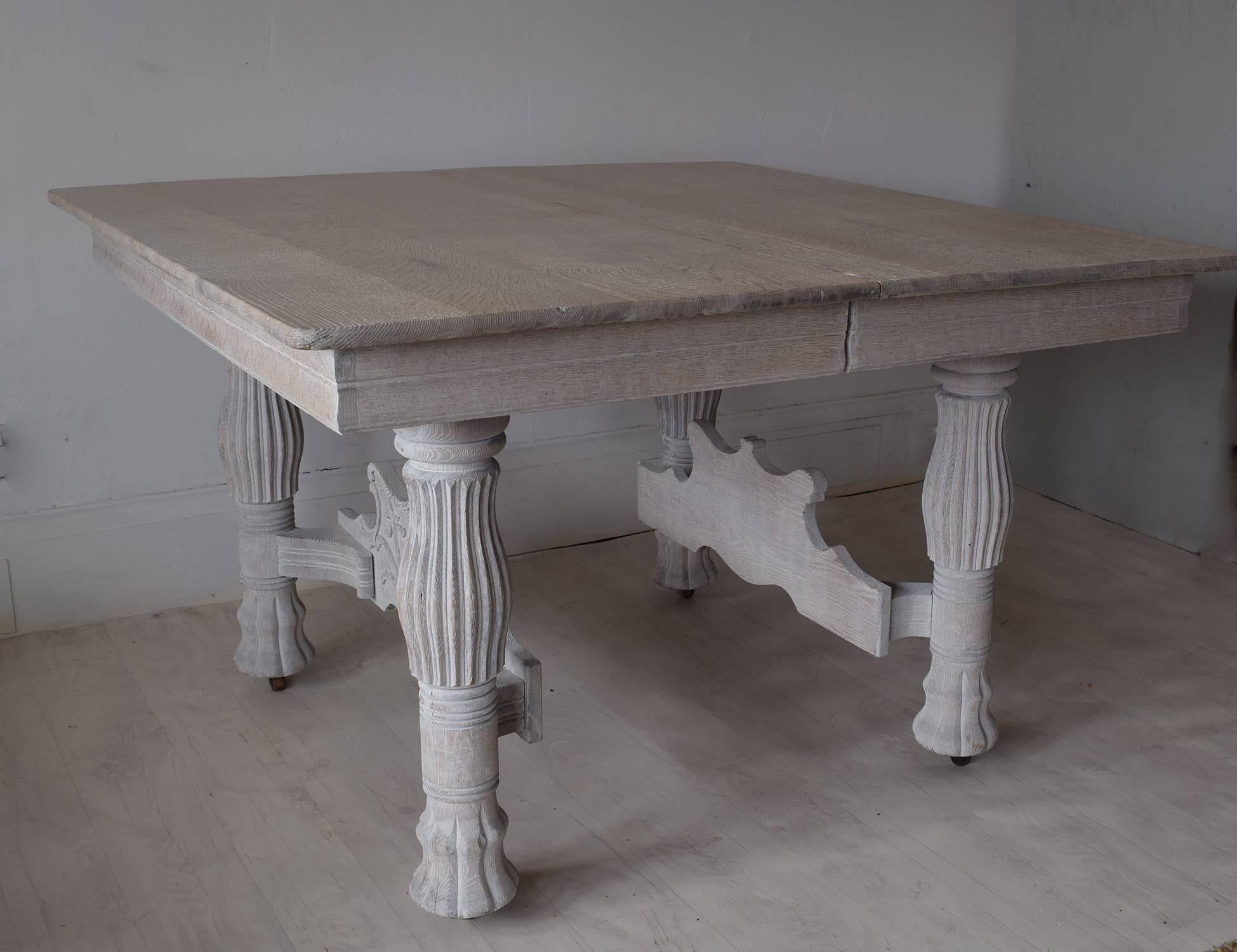 Large limed oak dining table which seats eight to ten people. Recently limed to enhance the beautiful grain and carving. Most unusual leg and panel at the table ends. It has three 12 inch leaves so there are a number of options length wise.
