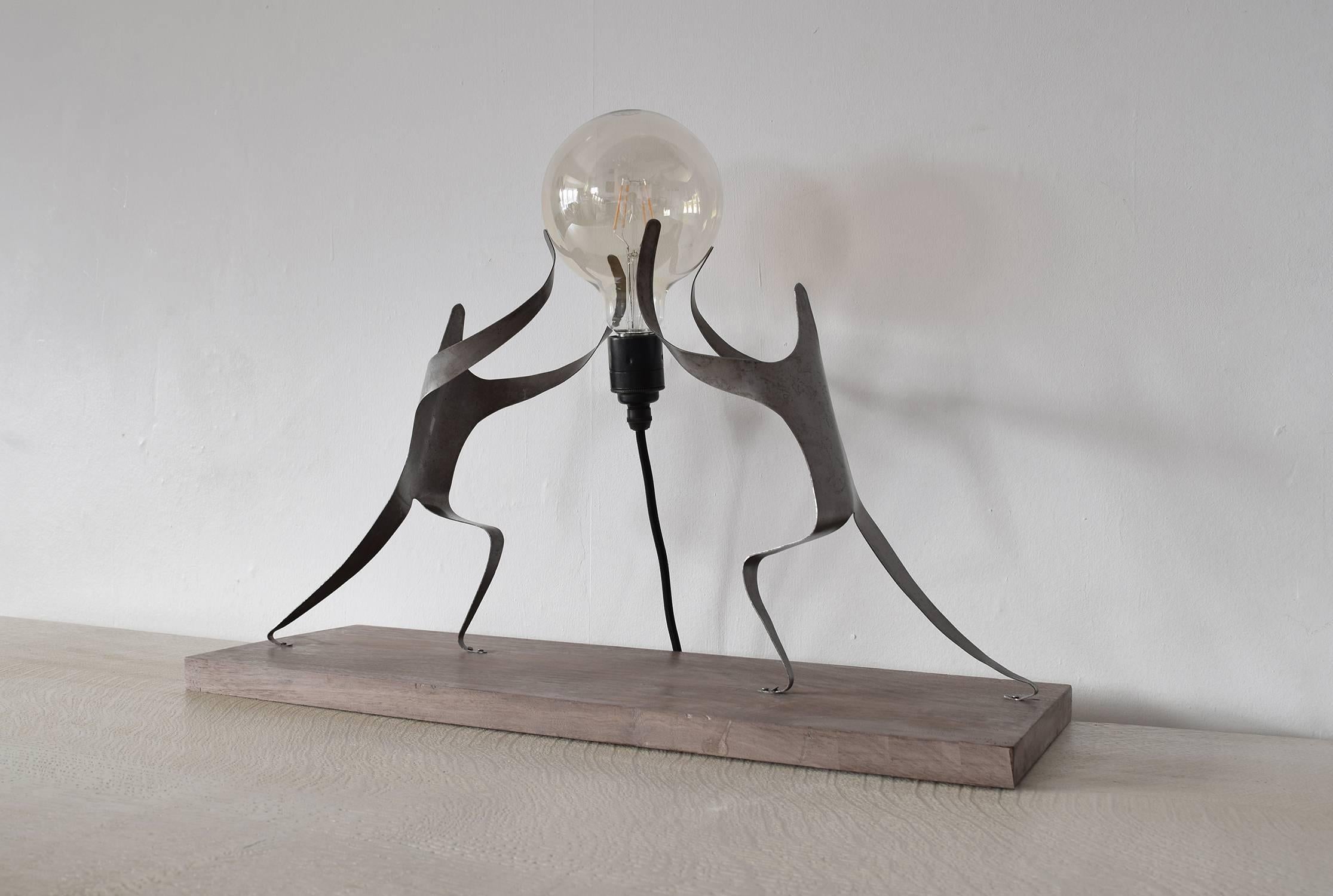 
A table lamp designed and handcrafted by Dominic Swire.

It can also function as a stand-alone sculpture.

Two bent steel figures stand on an American walnut base.

The piece has been exhibited at New Designers, Business Design Centre, Islington,