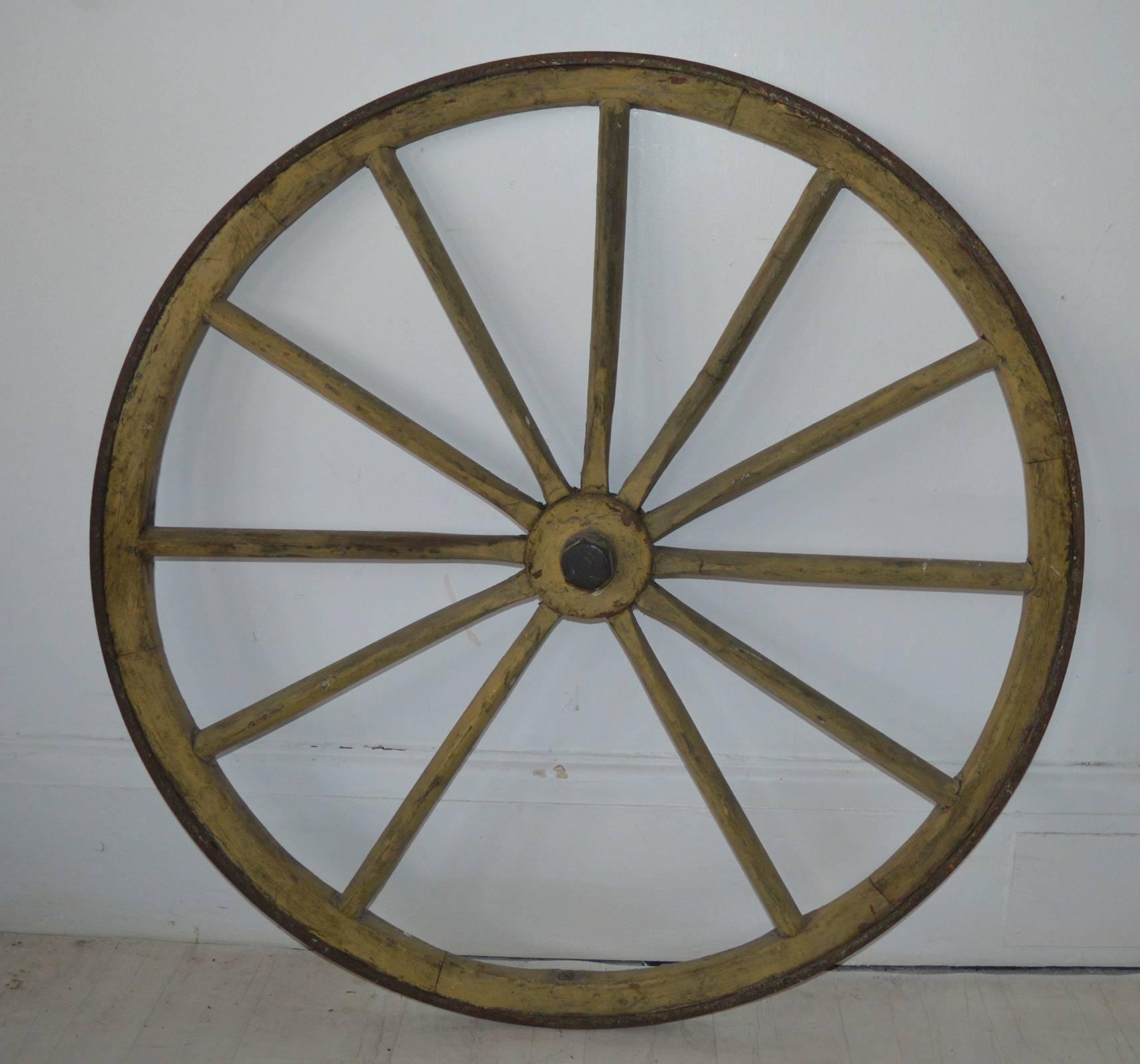 Great piece of Folk Art.

Painted wood with an iron band on the outer rim.

Beautiful color of pale yellow. "The color to die for".

Would look great mounted on a wall or even just rest against a wall.

One of the spokes is