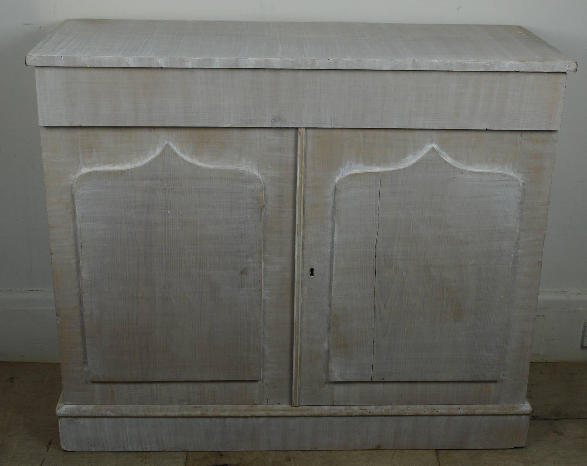 
The ultimate in understated elegance.

The piece has been repainted in white on the original pine. It has been limed so the grain is clearly visible.

The only ornamentation is the shield shape panel to the doors.

2 cupboard doors surmounted by a