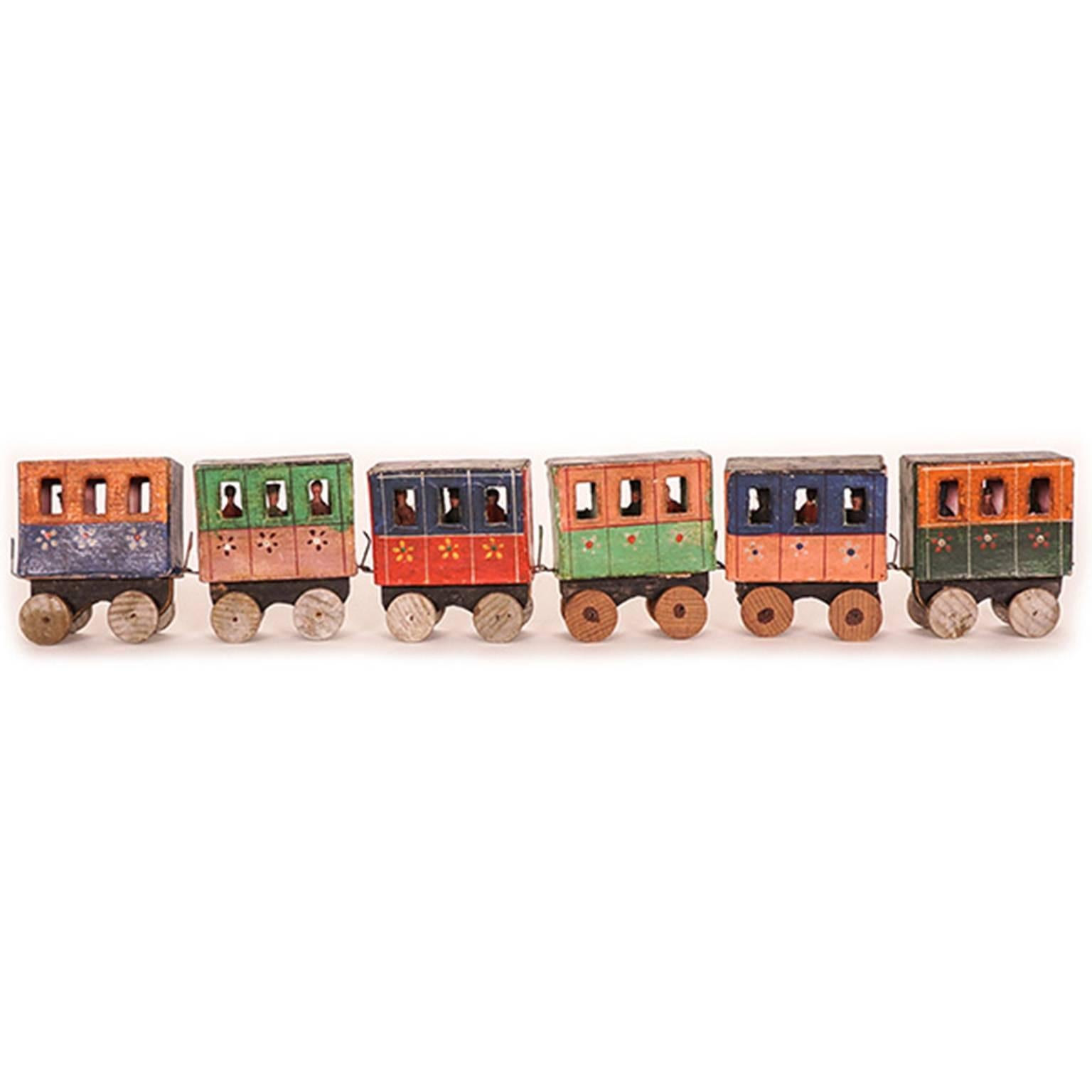 An early train set made in Olbernhau, a town of the district Erzgebirgskreis. Tiny papier machè figures sit within six hand-painted passenger coaches. Also included are five track sections which, together, form a slope and nine finely carved pine