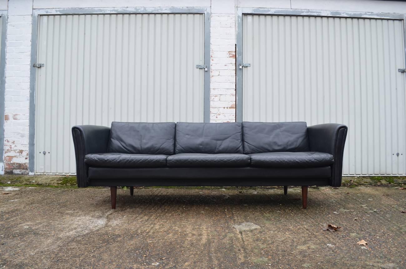 Danish midcentury three / four-seat sofa, 1960s.
In black leather with very nice patina. 

In good vintage condition. Removable cushions. No cracking or major damage, just the right amount of fade and age related wear.