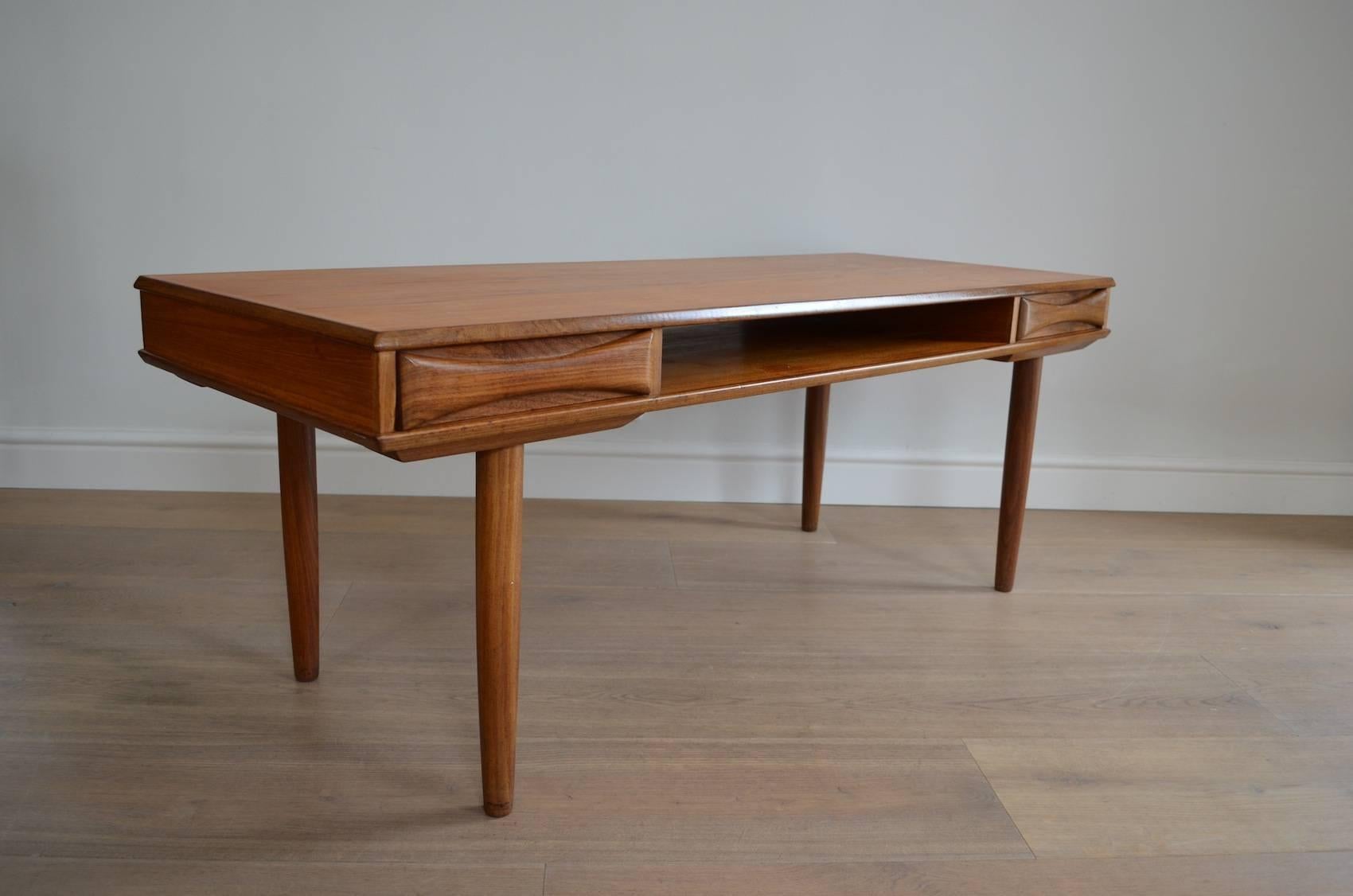 A Danish 1950s Arne Vodder style teak coffee table with a central bookshelf and sculptural double-sided drawers to each end.

Excellent original condition.