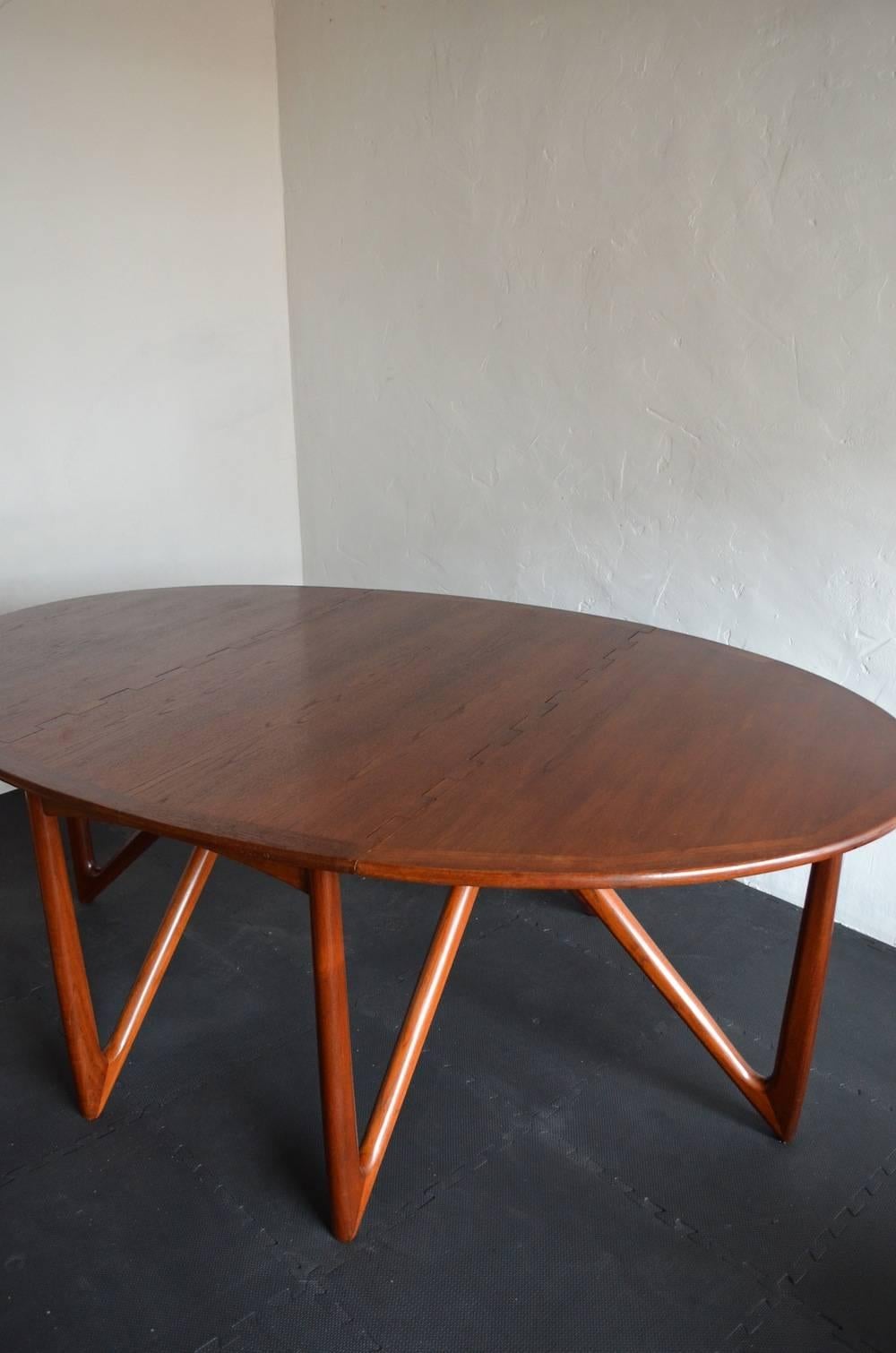 A stunning dark teak, oval table designed by Danish architect Kurt Østervig and manufactured by Jason Møbler in the 1960s. 

This table displays exceptional craftsmanship with beautiful trapezoid sculpted legs and hinged interlocking double drop