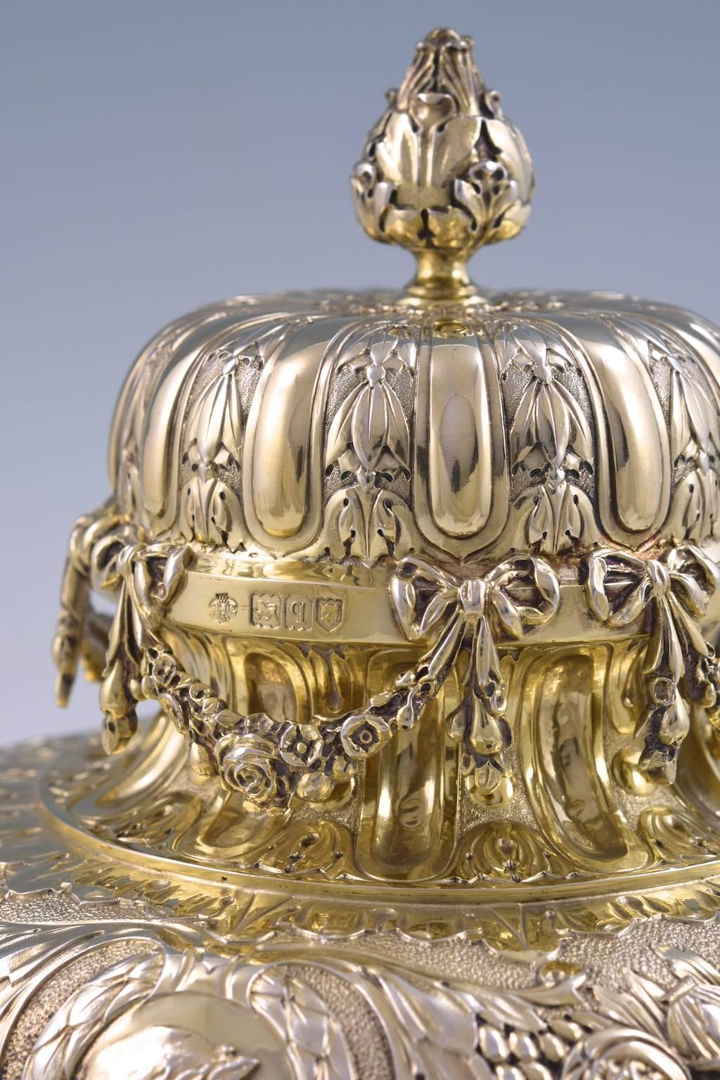 The body decorated with chased floral motifs, four laurel wreath lozenges with applied profile portraits in silver-gilt. The removable lid applied with cast floral swags

fully hallmarked on the base and on the rim of the lid

By William Hutton