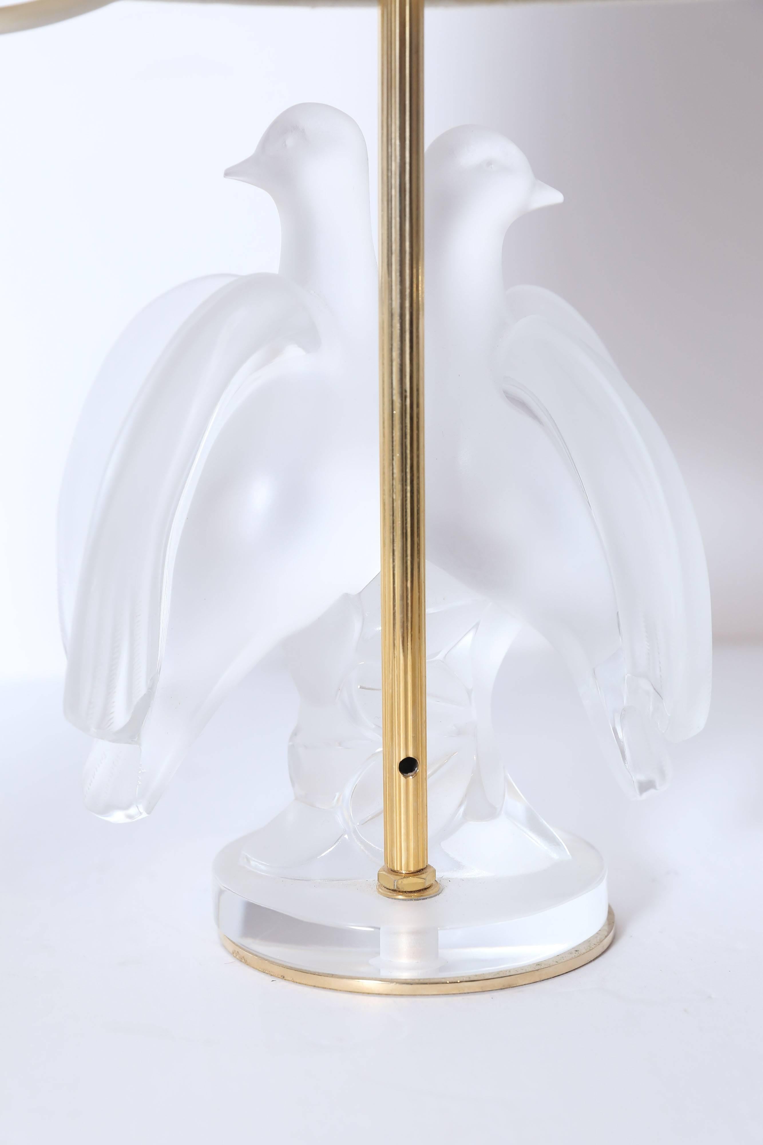 Designed by Marc Lalique and handcrafted in France.  Fashioned into an exquisite lamp.  It has graceful nature of clear crystal and sets the stage to showcase the masterful craftsmanship and the intricate design. Silk shade included.