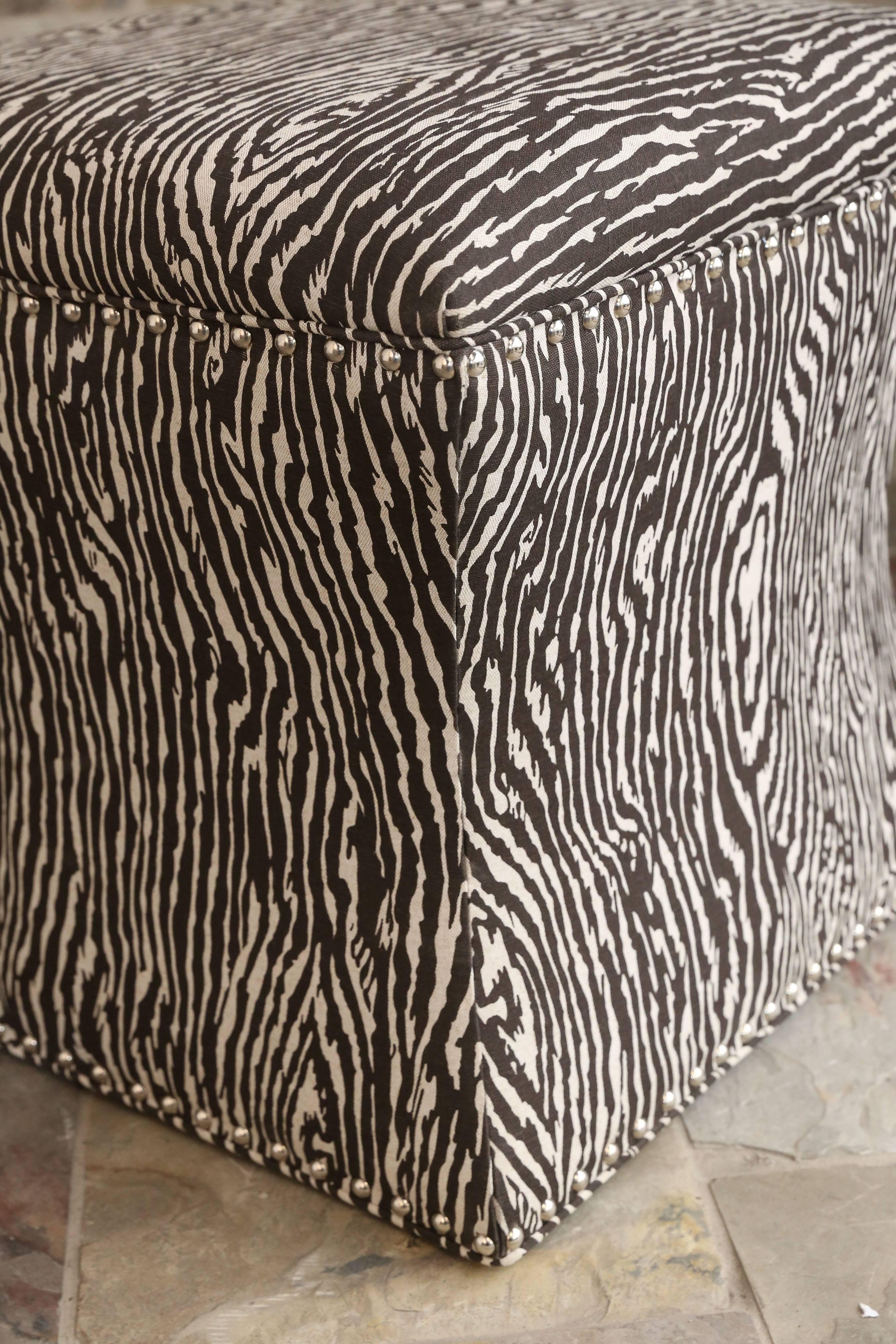 Lovely custom-made chocolate brown and cream ottomans in a wood print fabric finished with silver studs. Each ottoman gracefully curves in than out.