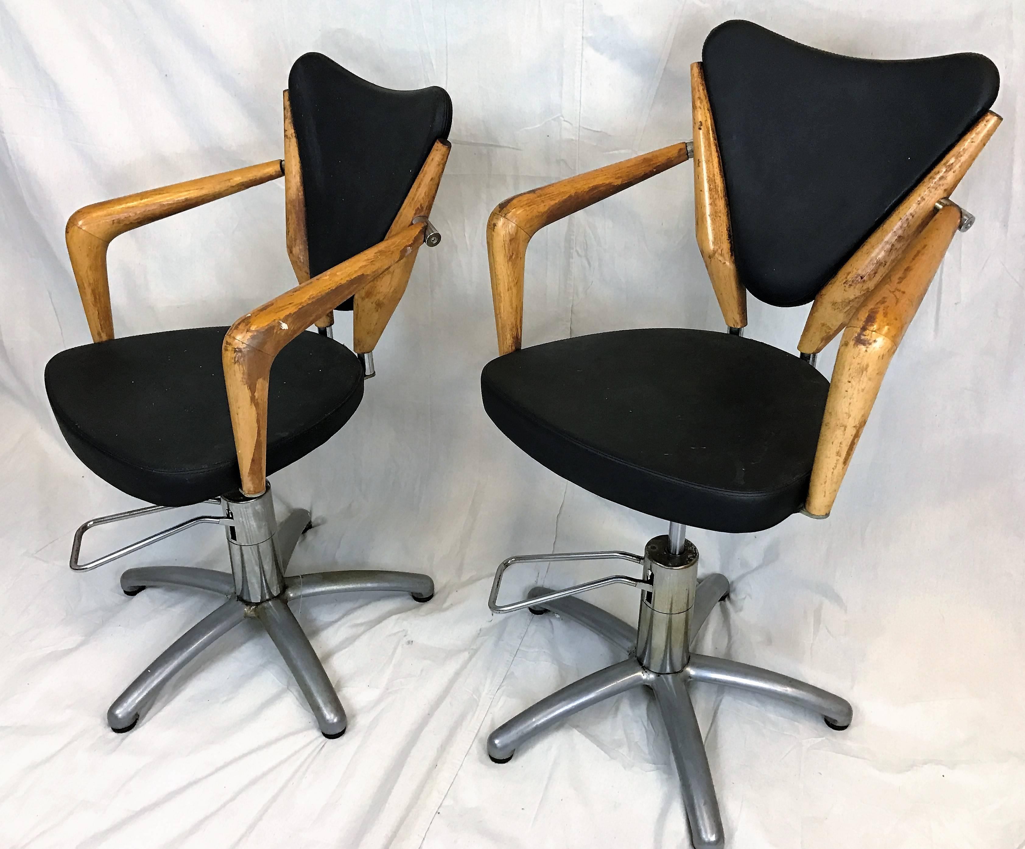 A pair of rare Italian hydraulic salon chairs with chrome and wood frame. Faux leather upholstered seats. Measurements when seat at full height 25