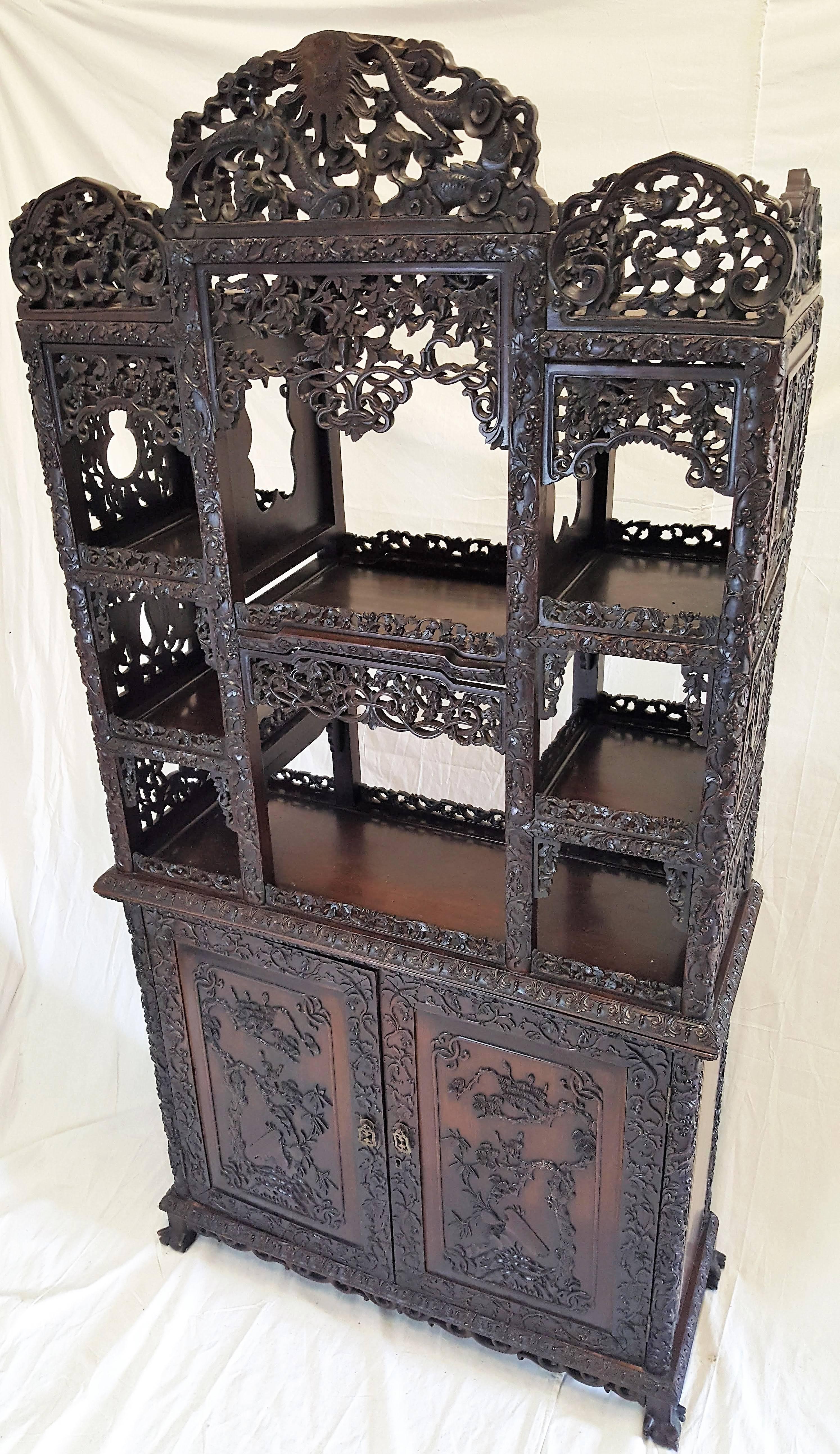 Expressing long life and happiness this beautifully highly reticulated Hong Mu curio cabinet is of the Qing dynasty. Birds, animals, berries, vines and the never ending coil are beautifully carved into this dark hong mu or rosewood cabinet.