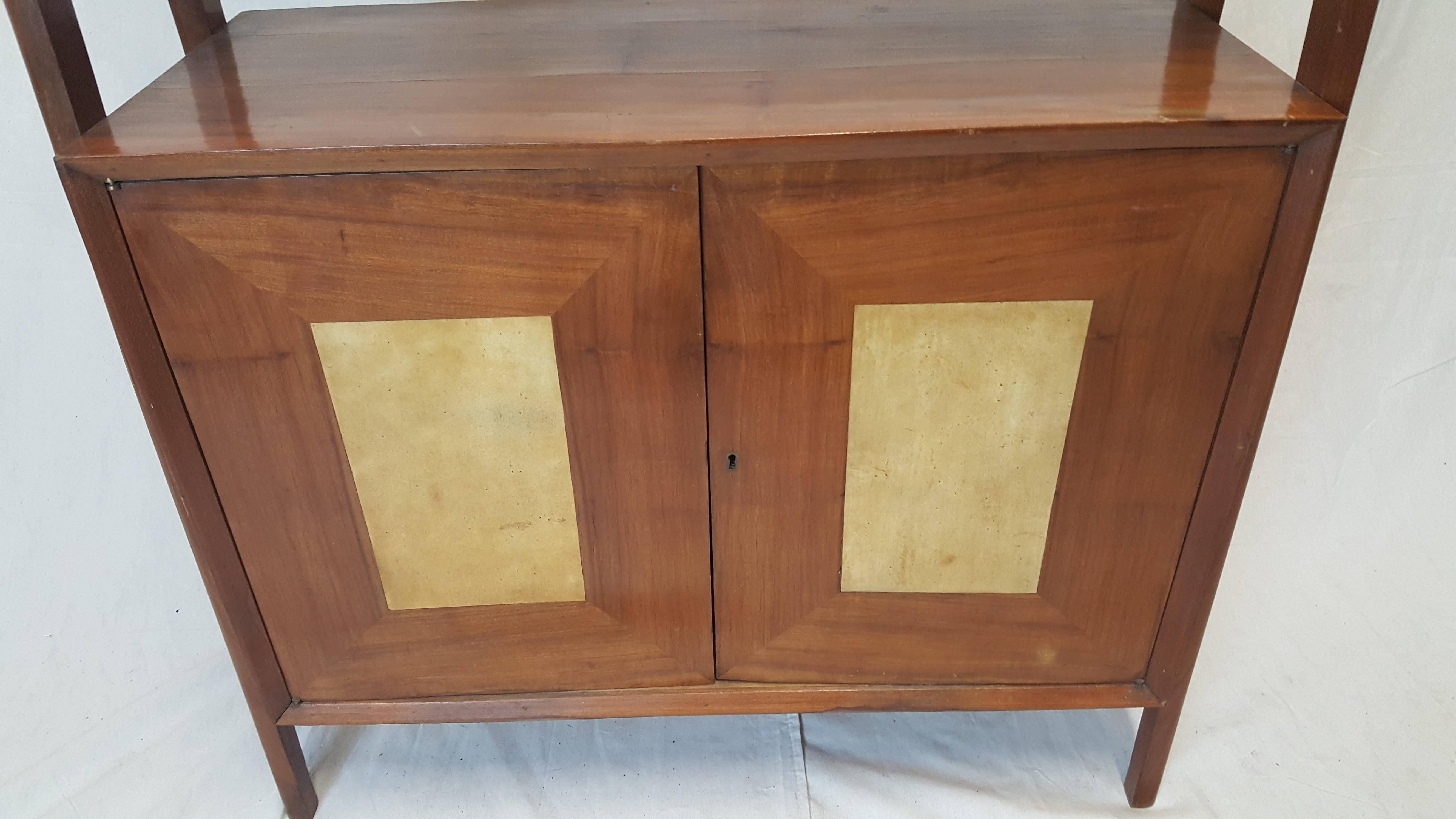 Gorgeous 1950s bookshelf made of natural walnut. The simplistic design accentuates the three shelves with double flats. The two-door cabinet with an insert of walnut opens to reveal two more shelves.