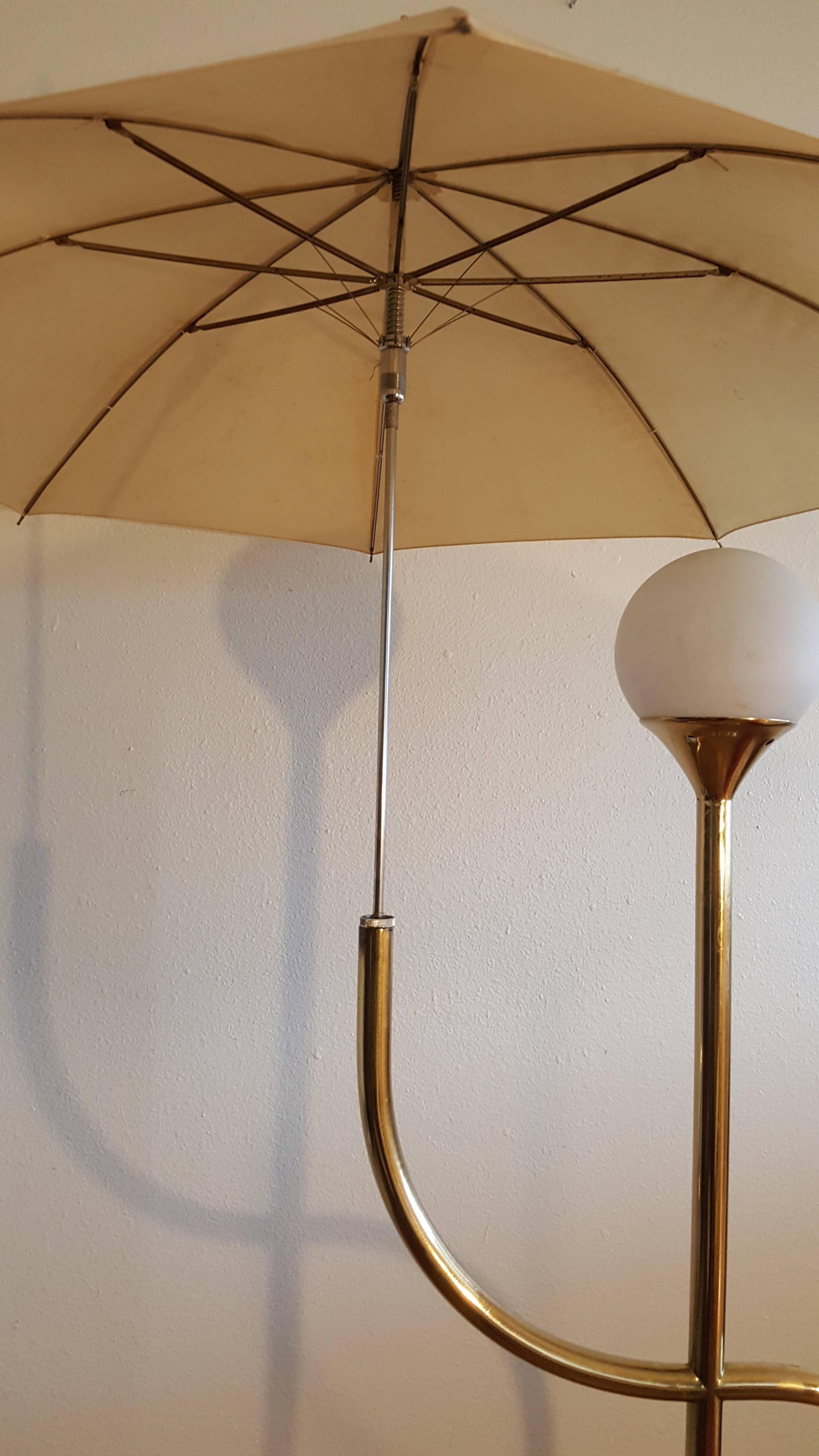 Adorable brass accent piece. Fully working umbrella is the focal point of this vintage floor lamp. Designed to look like a stick person carrying an umbrella. The umbrella open shades the light globe or close the umbrella for more light.
